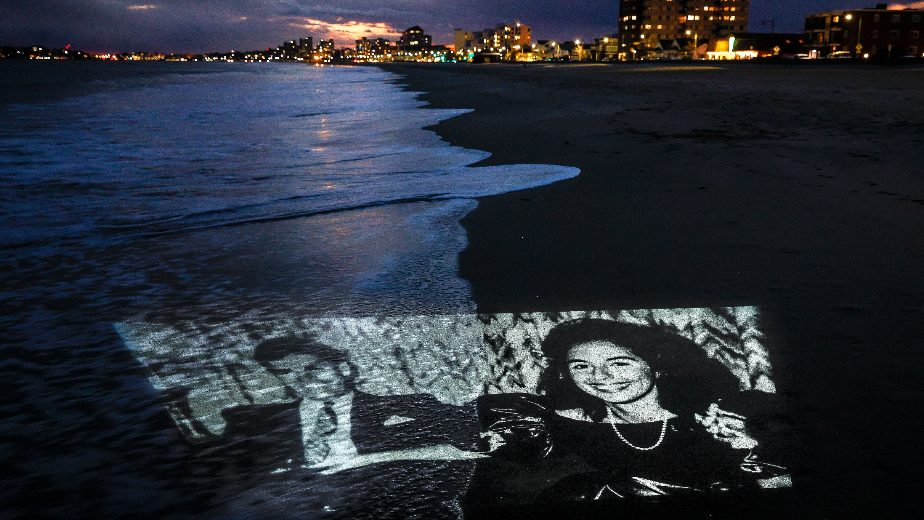 A photo of Charles and Carol Stuart is projected on Revere Beach.