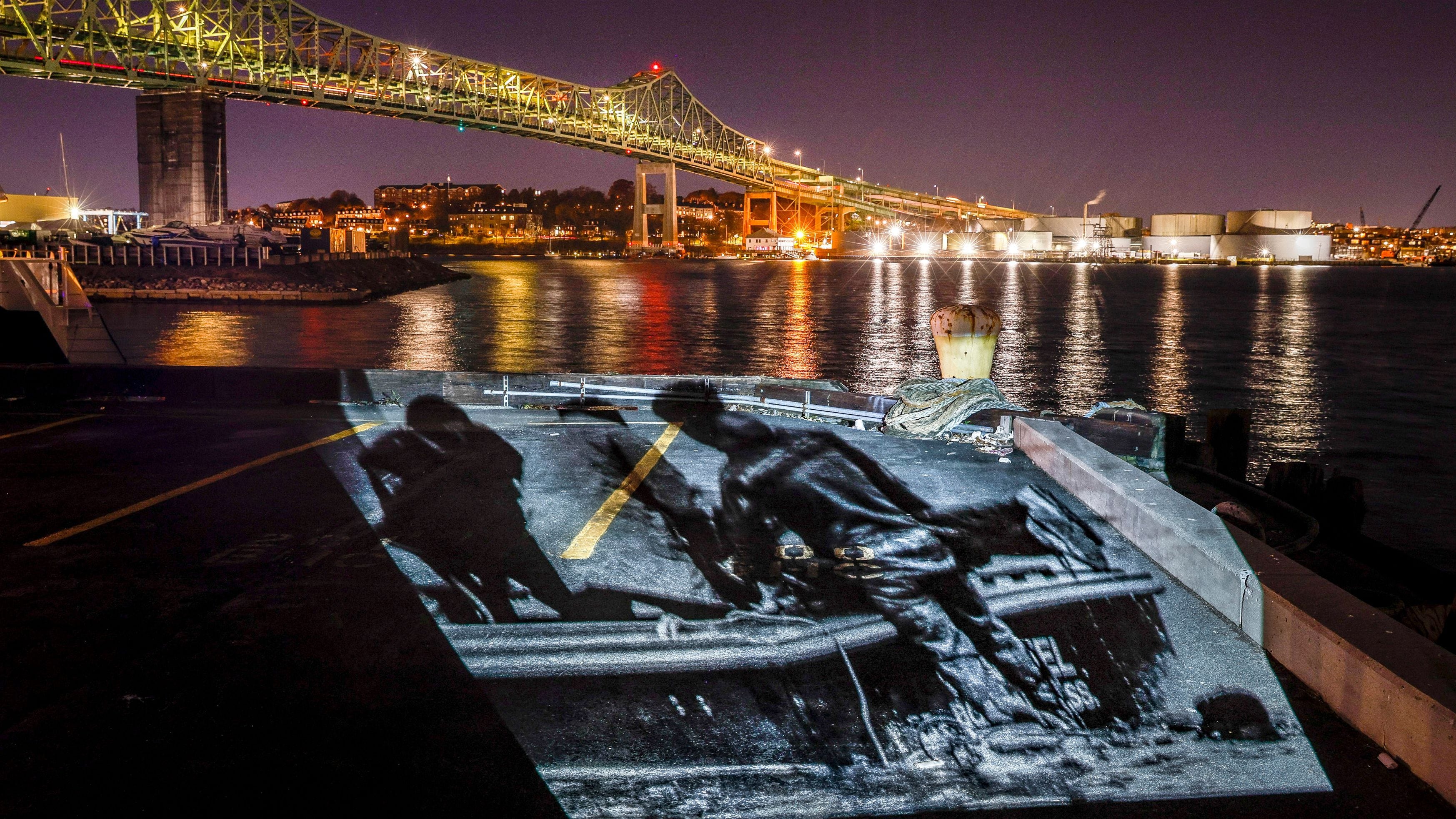 A projection of Charles Stuart's body being lifted from the water after State Police divers found him below the Tobin Bridge in Boston.