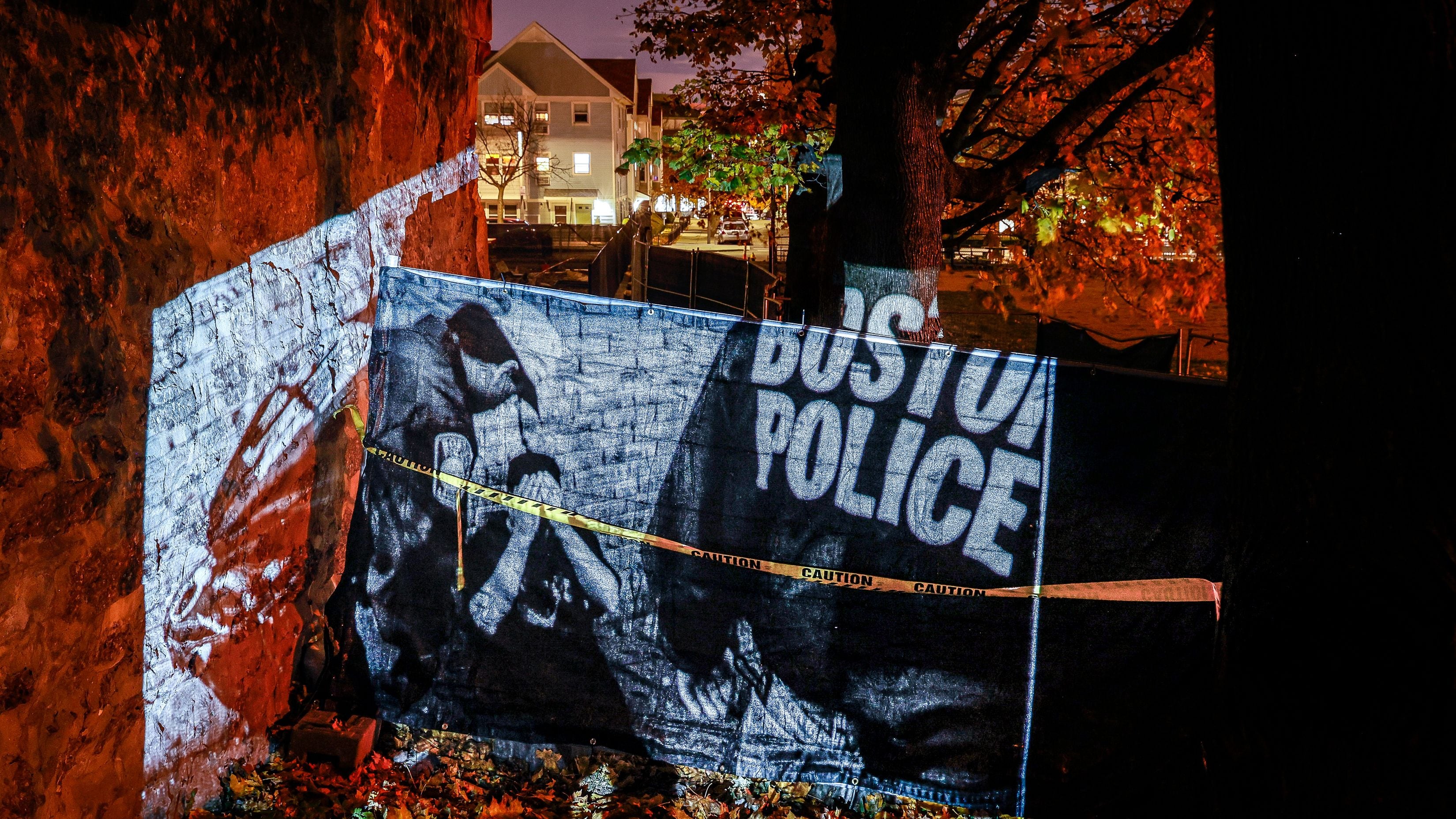 A projection of a man being detained by Boston police officers is projected in the former neighborhood of the Bennett family in Mission Hill.