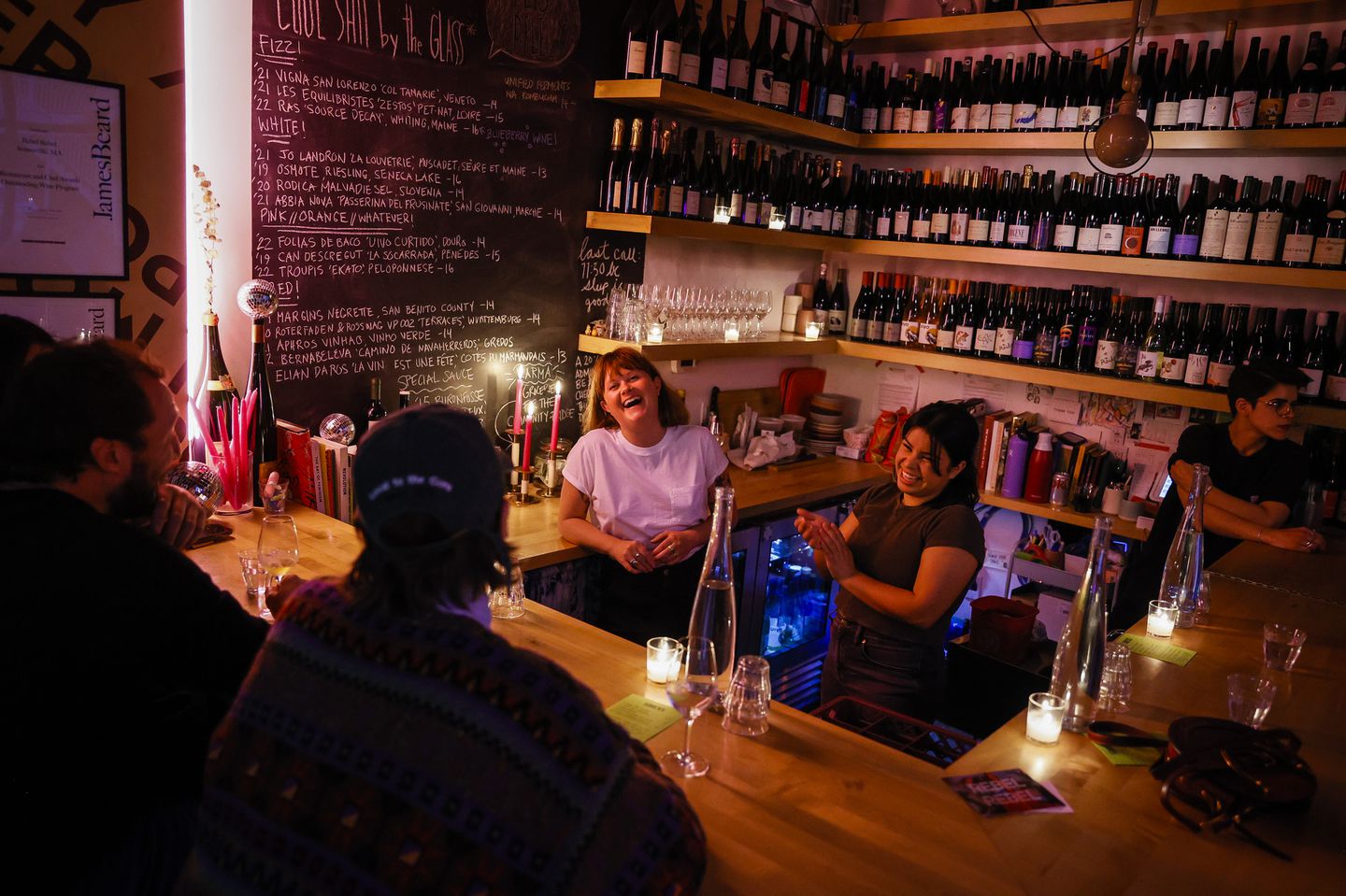 Lauren Friel (left) owner of Rebel Rebel, chatted with customers while working at her wine bar in Bow Market in Somerville. The restrictive Boston liquor license system has pushed throngs of innovative chefs to neighborhood towns with laxer laws, including Brookline, Somerville, and Cambridge.