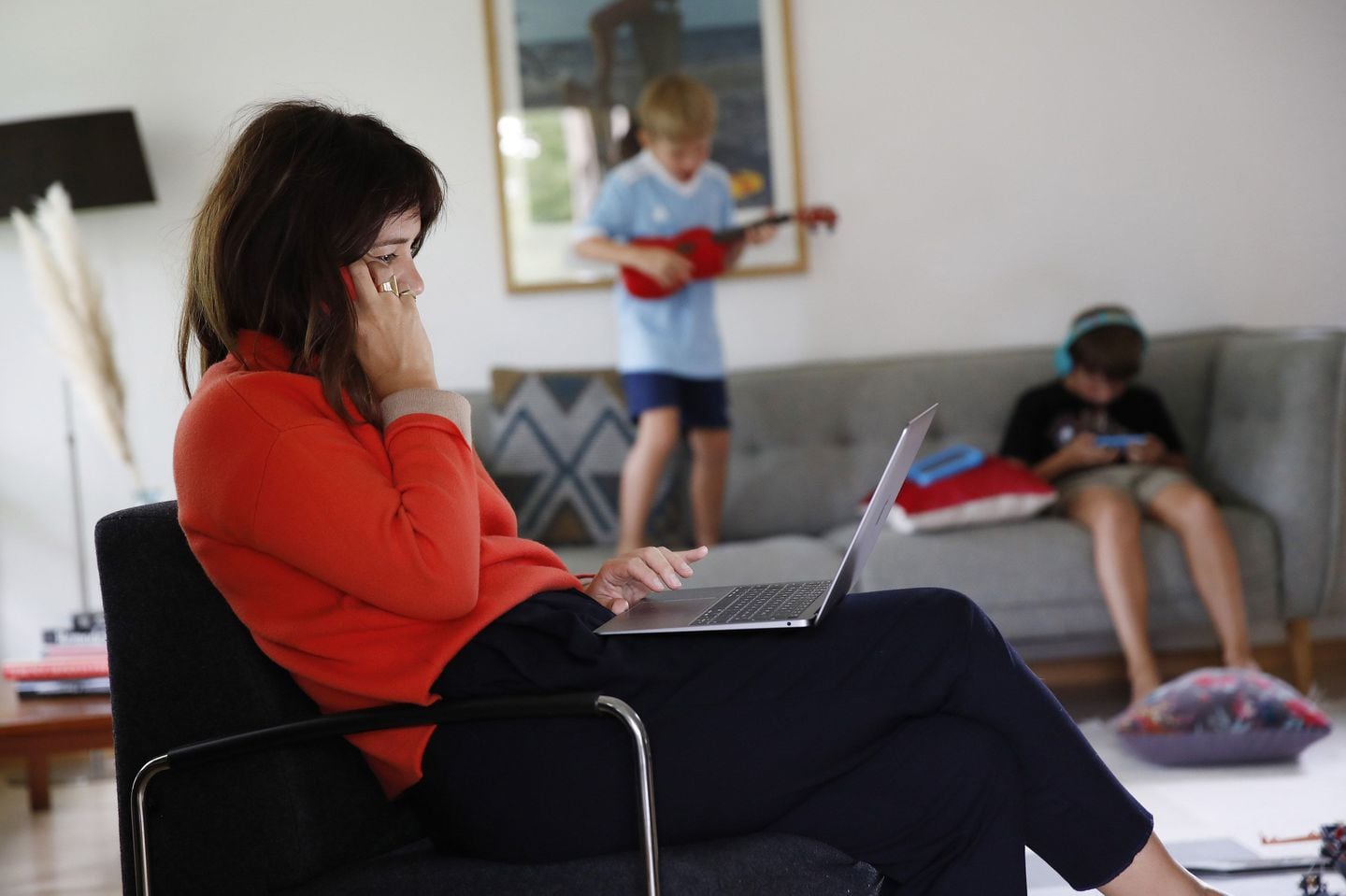 A woman works at a laptop computer in a lounge as children play beyond in this arranged photograph taken in Bern, Switzerland, on Wednesday, Aug. 19, 2020. The biggest Wall Street firms are navigating how and when to bring employees safely back to office buildings in global financial hubs, after lockdowns to address the Covid-19 pandemic forced them to do their jobs remotely for months. Photographer: Stefan Wermuth/Bloomberg