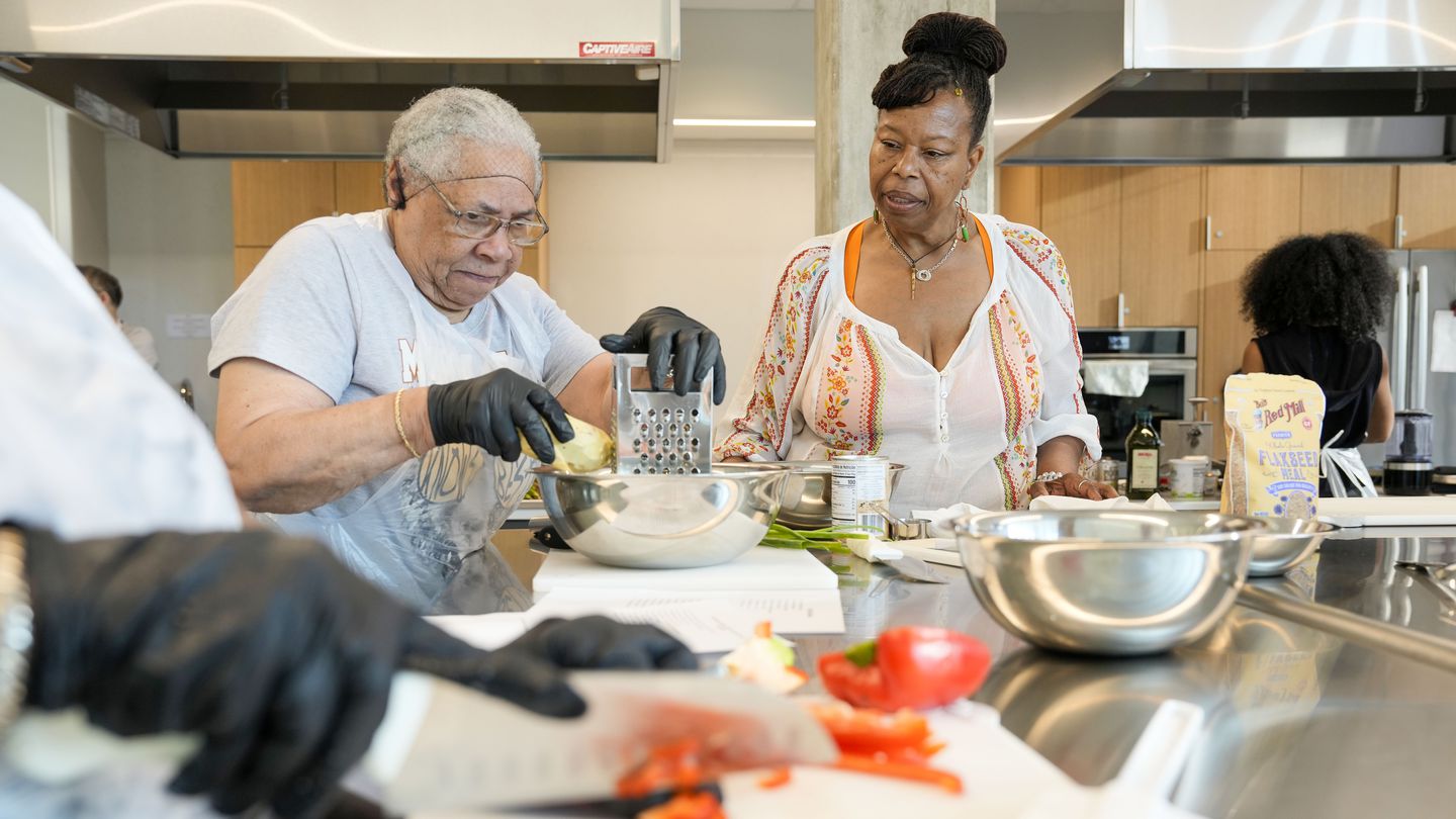 Glorya Fernandez (right) taught Wynne Blair how to cook black-eyed pea fritters during the Juneteenth celebration in Boston. Fernandez is a local chef that hosts plant-based meal cooking demonstrations and other nutritional instruction initiatives through her company gogobytes.