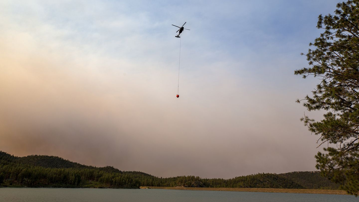 A helicopter collects water from Mescalero lake near the Inn of the Mountain Gods Resort in Ruidoso, N.M., as authorities fight wildfires on June 18.