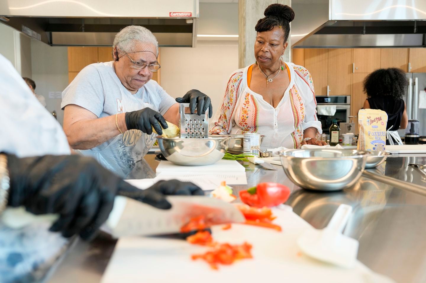 Glorya Fernandez (right) taught Wynne Blair how to cook black-eyed pea fritters during the Juneteenth celebration in Boston. Fernandez is a local chef that hosts plant-based meal cooking demonstrations and other nutritional instruction initiatives through her company gogobytes.