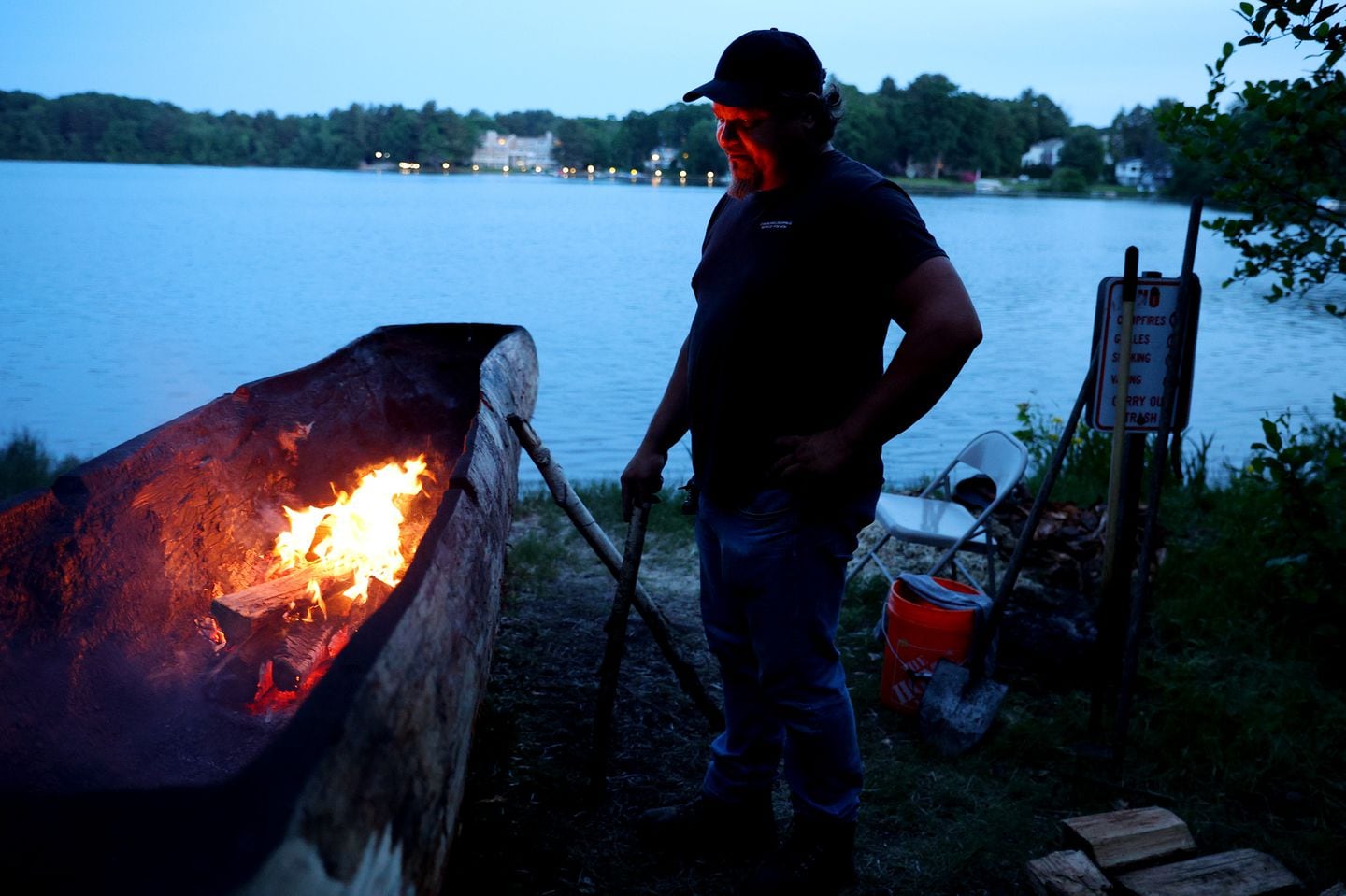 The fire from the inside of a dugout canoe, referred to by Indigenous people as a mishoon, lit the face of George Bearclaw as he took the night shift to keep an eye on the flames and continue to scrape and shape the mishoon on the shores of Lake Quinsigamond in Shrewsbury. For the first time since the 1640s, a mishoon burned on the shores of Lake Quinsigamond as  members of the Hassanamisco band of the Nipmuc held a weeklong traditional burn.