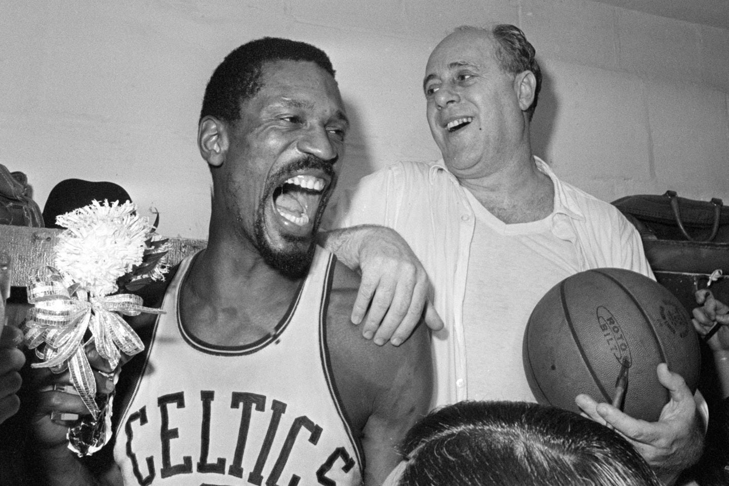 Boston Celtics' Bill Russell, left, held a corsage sent to the dressing room as he celebrated with Celtics coach Red Auerbach after defeating the Los Angeles Lakers, 95-93, to win their eighth-straight NBA Championship, in Boston, April 29, 1966.