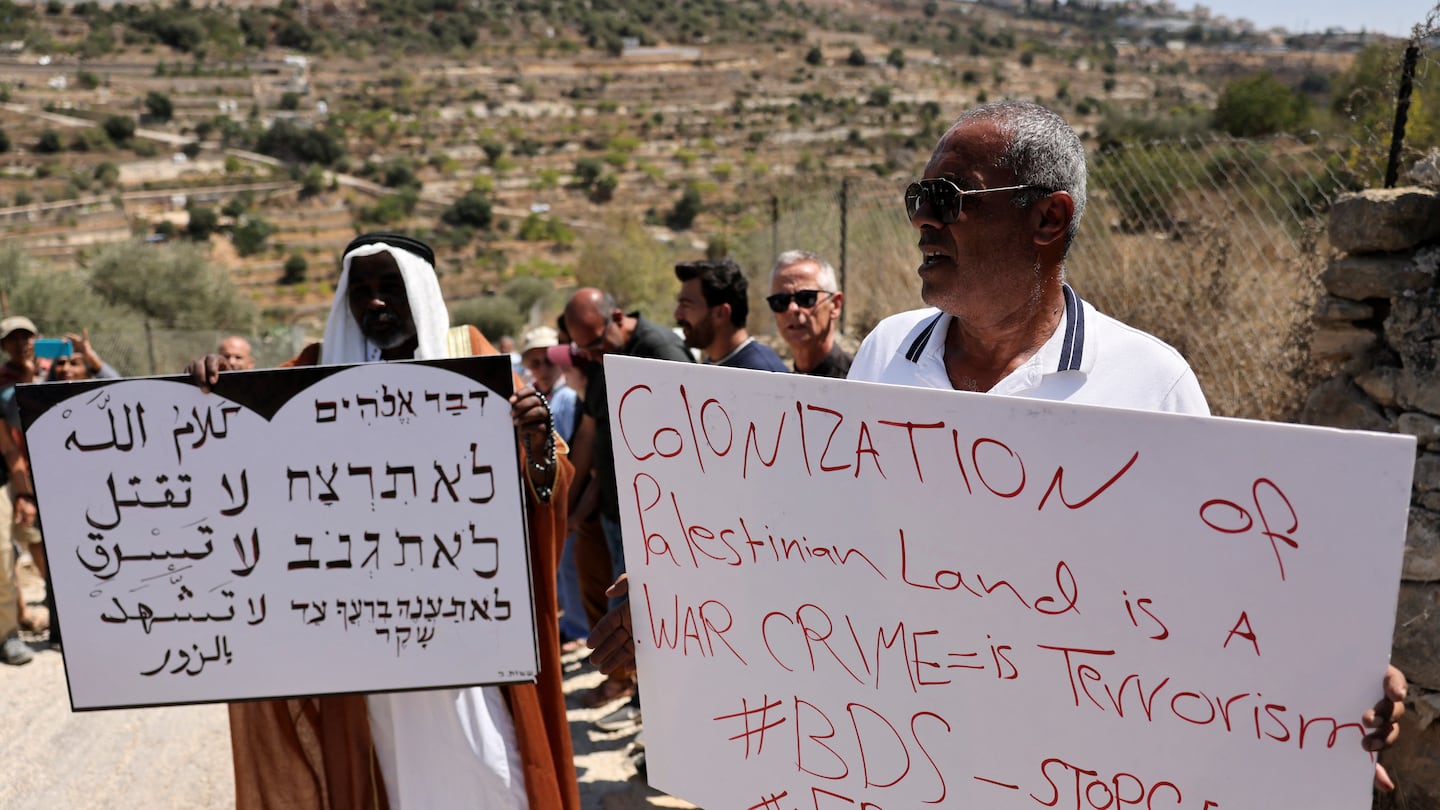 A demonstrator holds a sign showing in Arabic and Hebrew three of the biblical Ten Commandments "do not kill, do not steal, do not give false testimony", during a protest vigil in Beit Jala in the occupied West Bank on September 3, 2024.