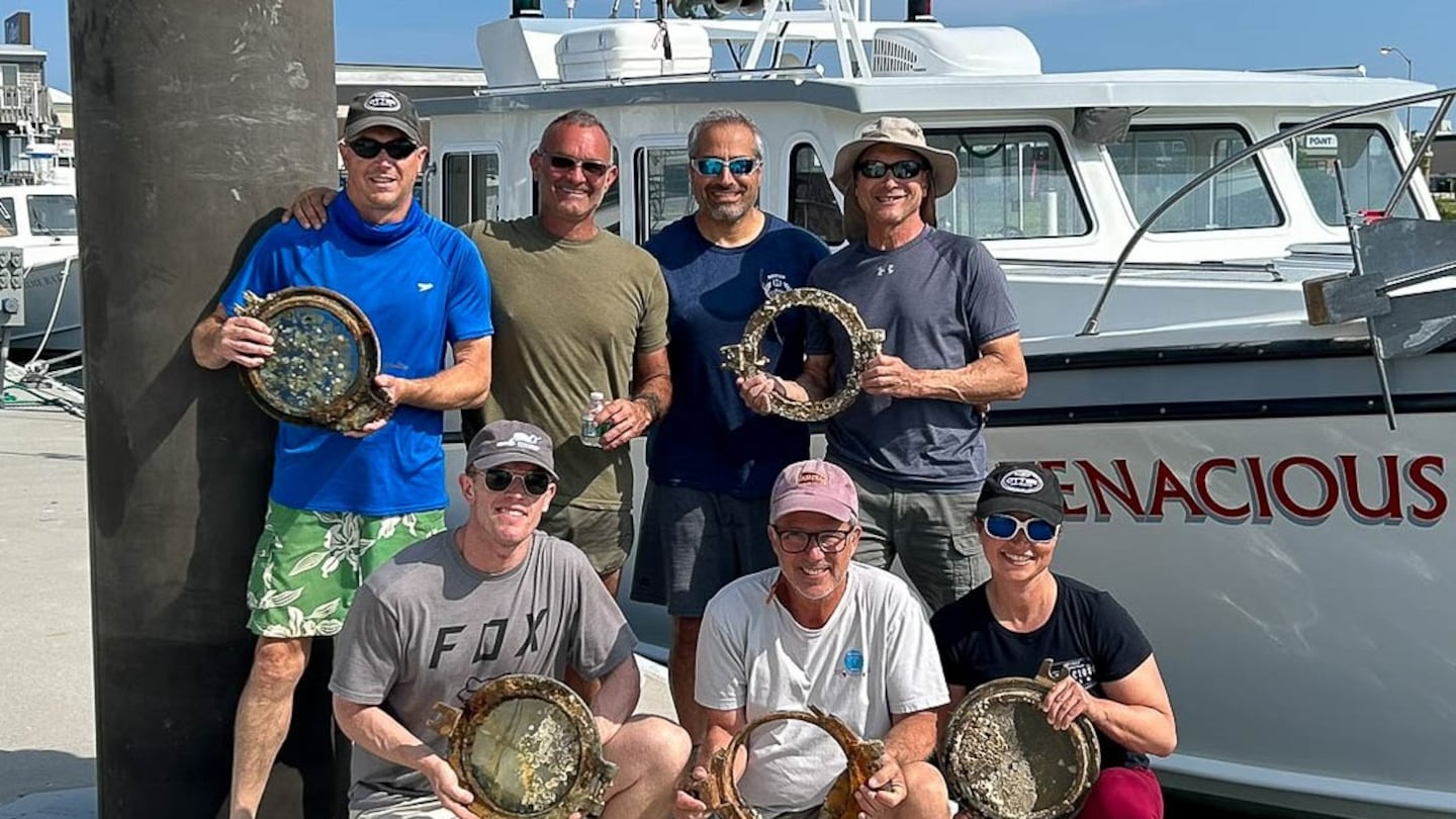 Members of the team from Atlantic Wreck Salvage held portholes pulled from the wreckage of Le Lyonnais, alongside the crew's boat, the D/V Tenacious.