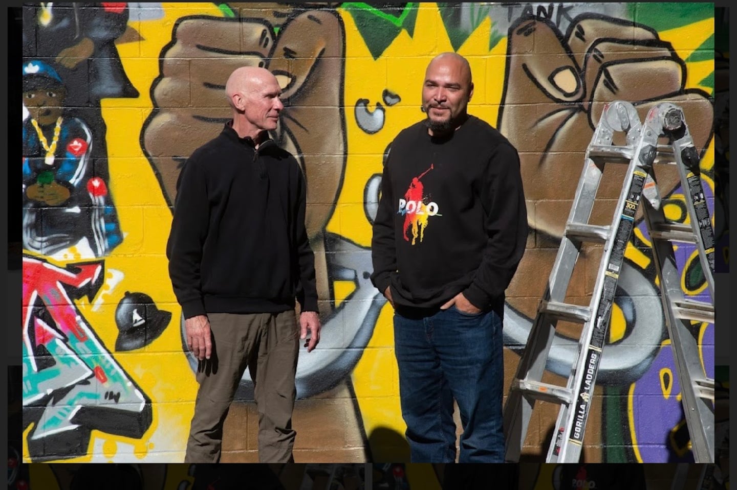 Former Boston police officer Paul Joyce, left, with the graffiti artist Alvin Colon in front of a mural in Norwood that Colon made for Joyce's new book, “It Started With the Hats: The Life Experiences of Boston’s Founding Street Gang Members."