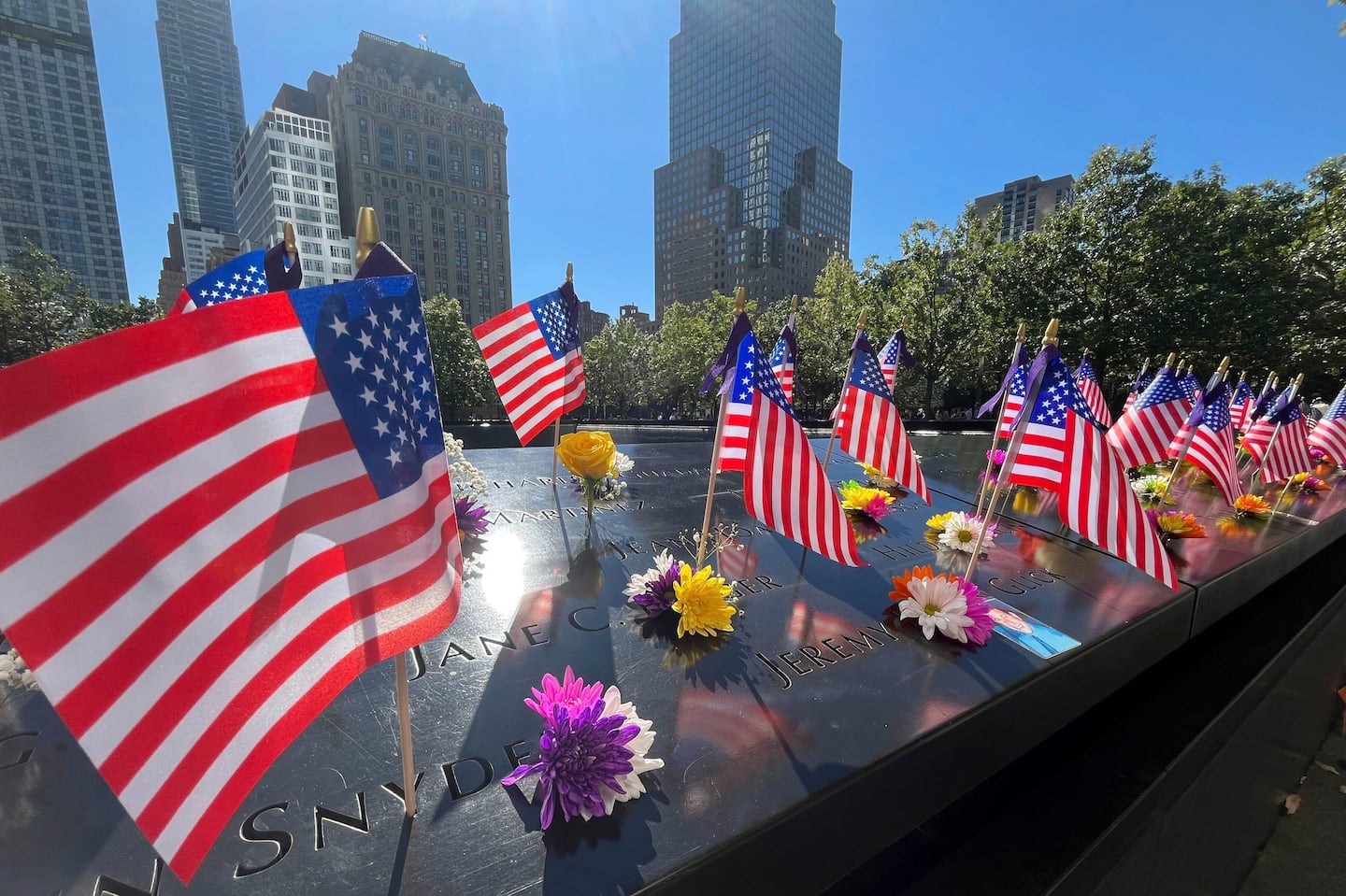 Flags and flowers are placed by the names of those killed during the Sept. 11, 2001, attacks at the reflecting pools at the National September 11 Memorial & Museum, Sept. 10, in New York.