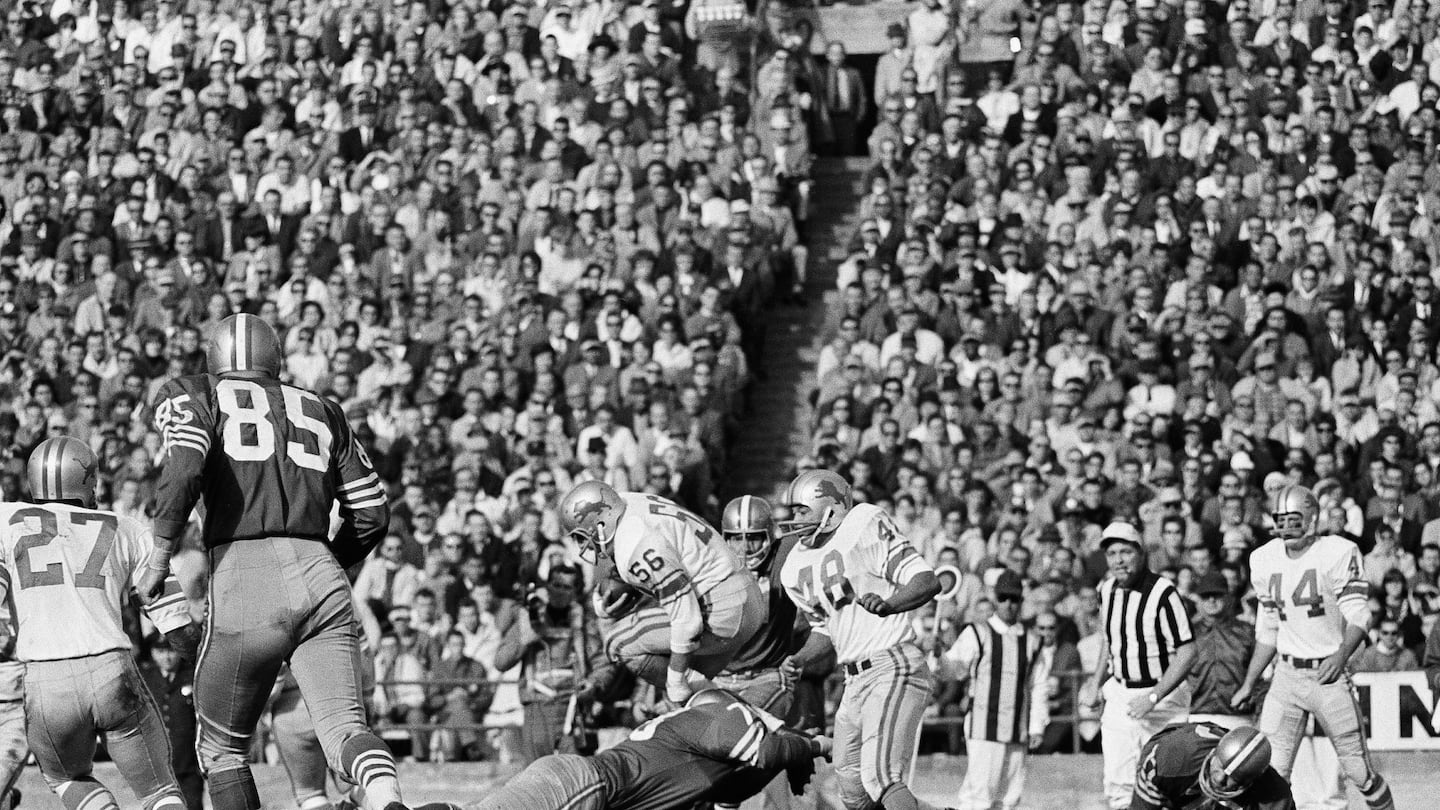 Detroit middle linebacker Joe Schmidt tucked his legs under as he evaded a San Francisco tackler after intercepting a 49er pass in 1965.