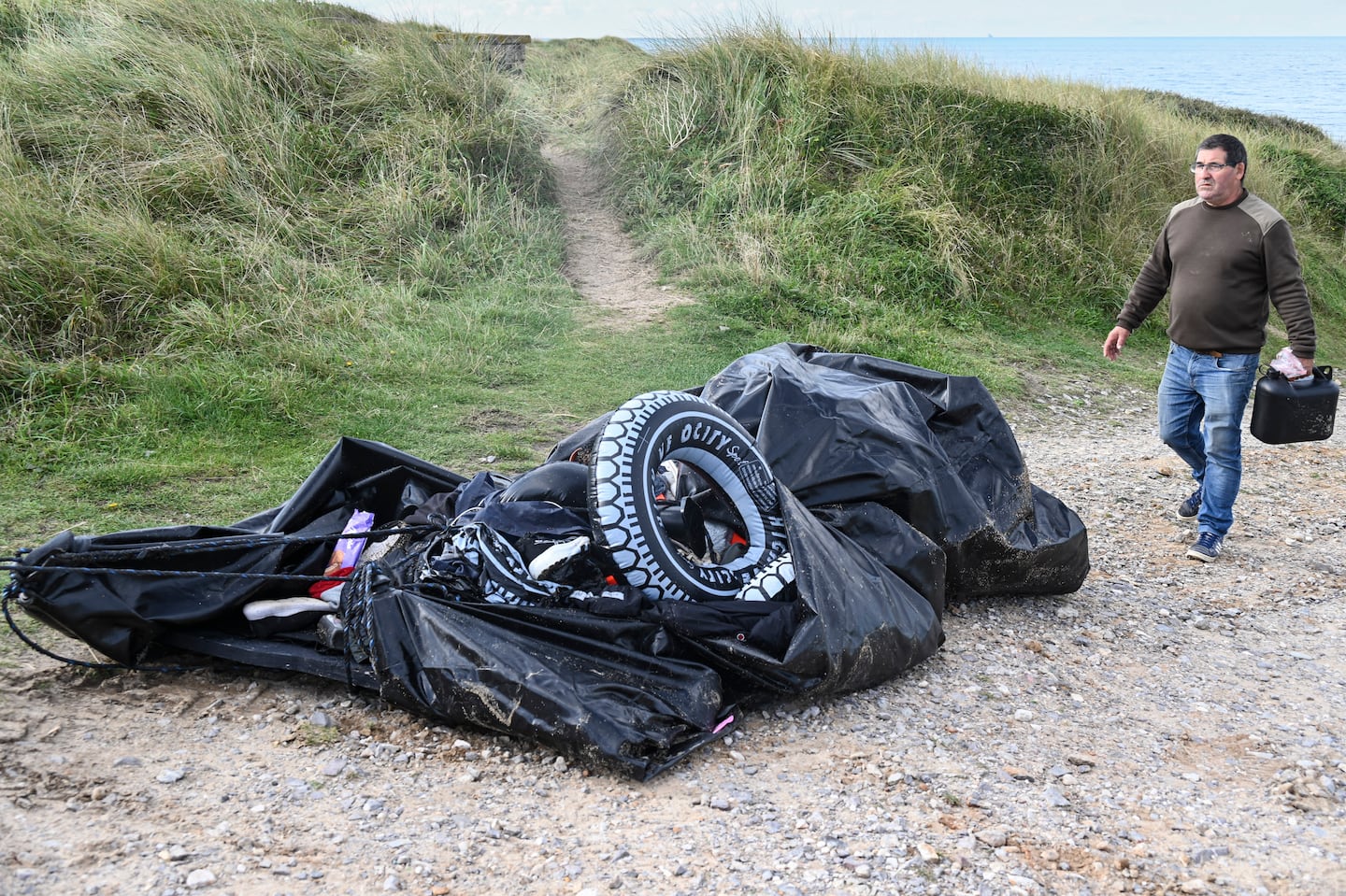 A fisherman walks next to a damaged migrants' boat after a failed attempt to cross the English Channel that led to the death of 8 people near the beach of Ambleteuse, northern France on Sept. 15.