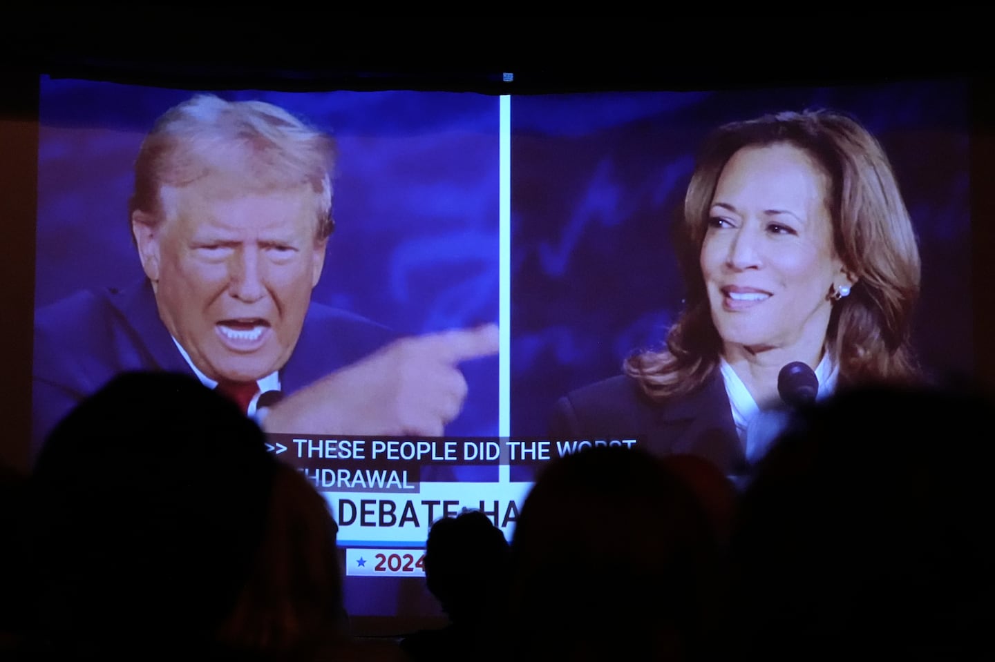 Republican presidential nominee former president Donald Trump, left, and Democratic presidential nominee Vice President Kamala Harris are seen on a screen during a presidential debate as people watched in Portland, Maine.