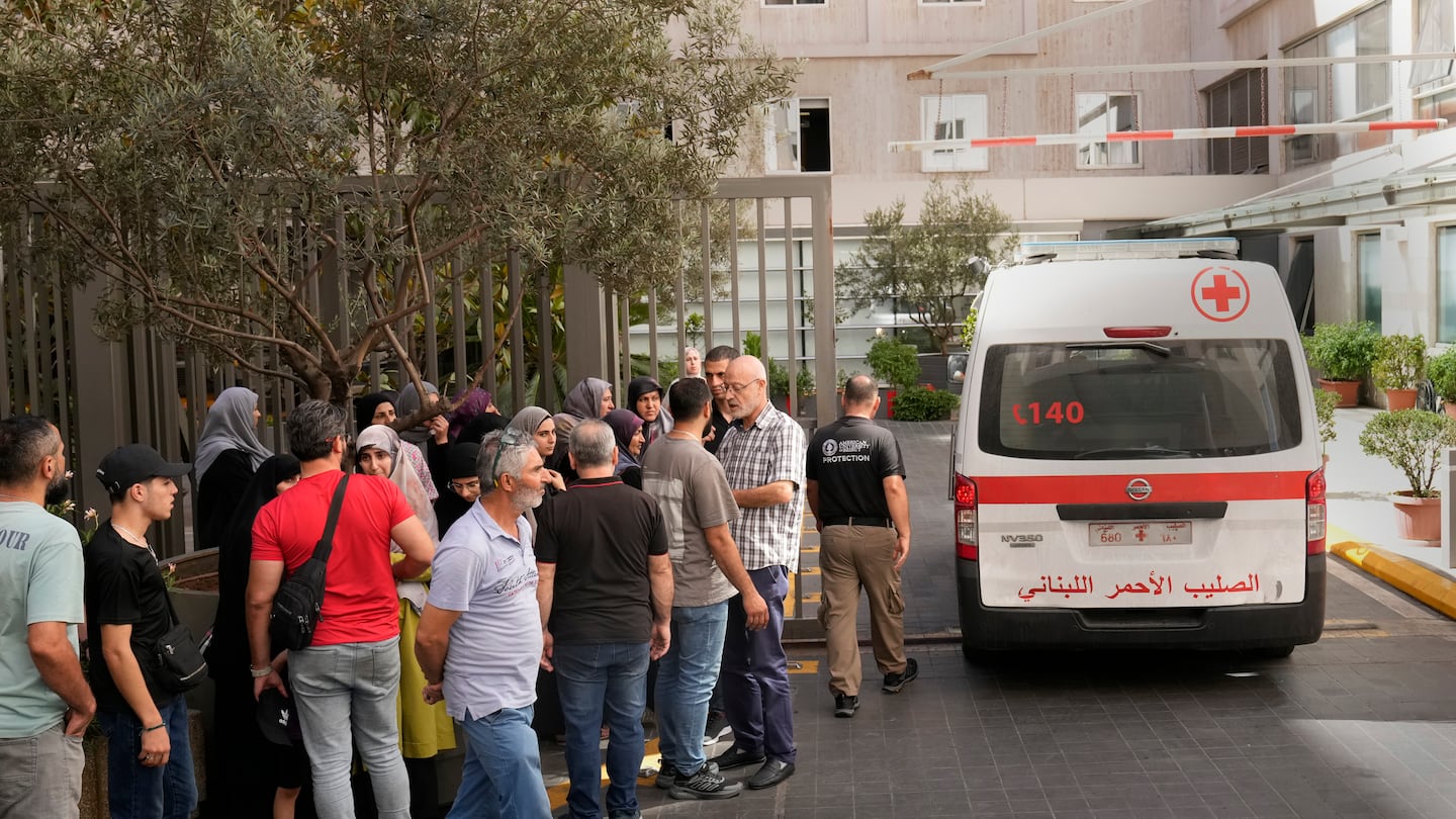 CORRECTS DAY TO TUESDAY WHEN INJURED Lebanese Red Cross ambulance passes next of the families of victims who were injured on Tuesday by their exploding handheld pagers, at the emergency entrance of the American University hospital, in Beirut, Lebanon, Wednesday, Sept. 18, 2024. (AP Photo/Hussein Malla)