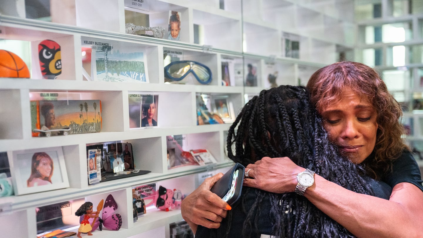 Aimee Giles-Scott (facing camera) gets a hug after looking at the Gun Violence Memorial Project in City Hall featuring her son Myles van Frazier. He was shot and killed by police in Chicago. Giles-Scott said he was having a bipolar episode.