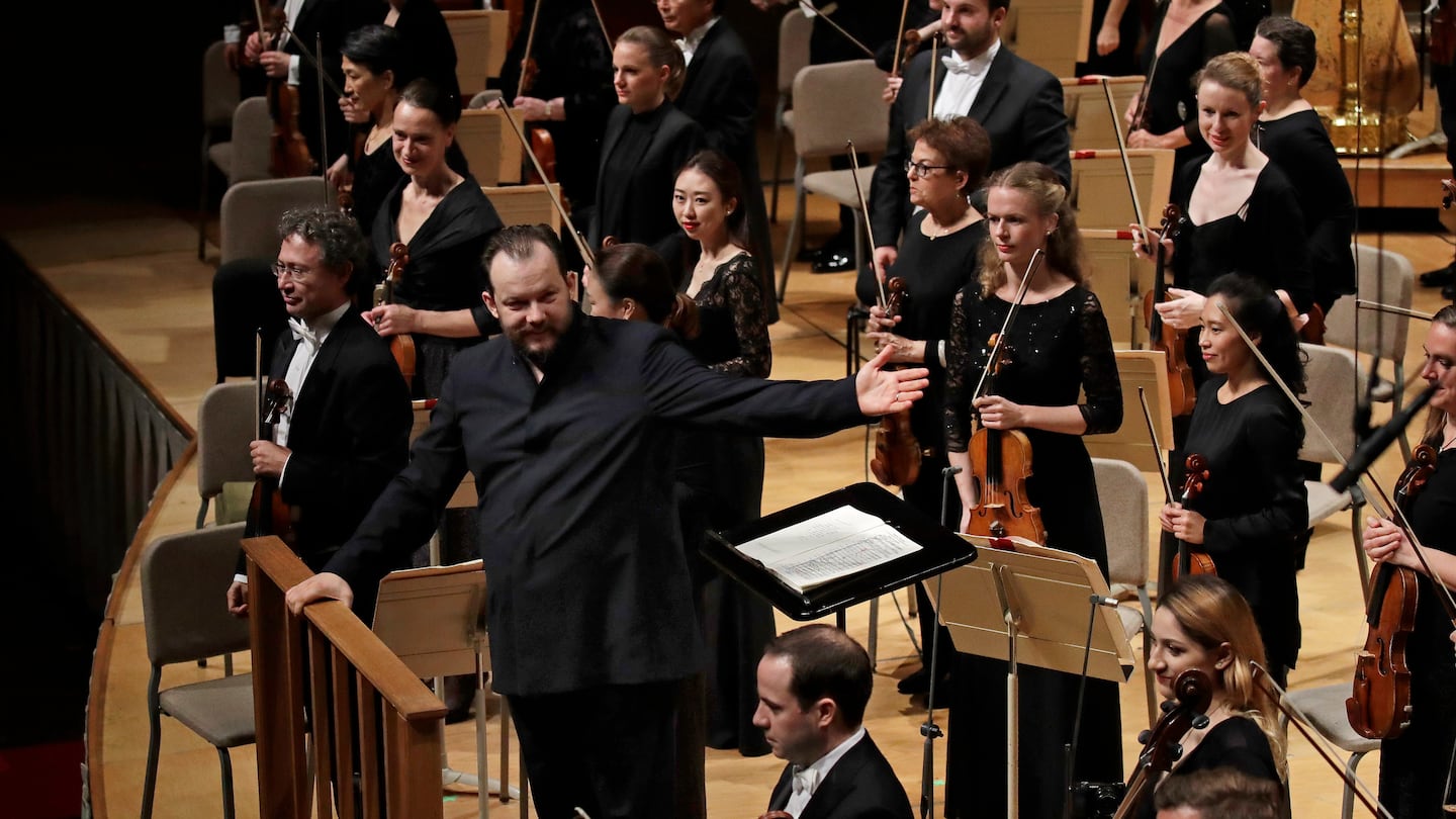 Andris Nelsons gestured towards the musicians before conducting a joint concert of the Boston Symphony Orchestra and Germany's visiting Leipzig Gewandhaus Orchestra at Symphony Hall in Boston on Oct. 31, 2019. In taking up a second post in Leipzig, the conductor has forged a unique alliance between both organizations.