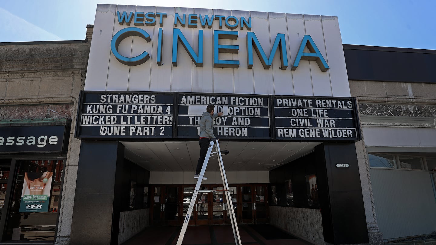 Maintenance man Adonis Deacon changes the movies list outside the theater.