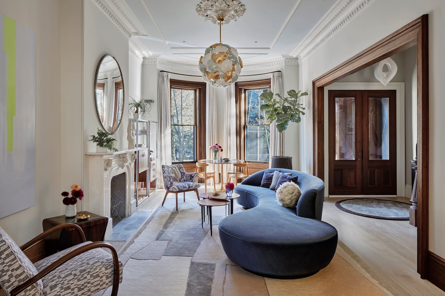 A vintage convex railroad mirror from Europe provides an artful reflection of the front parlor and formal entry, which showcases a plaster pendant light made by French artisan Alexandre Logé.