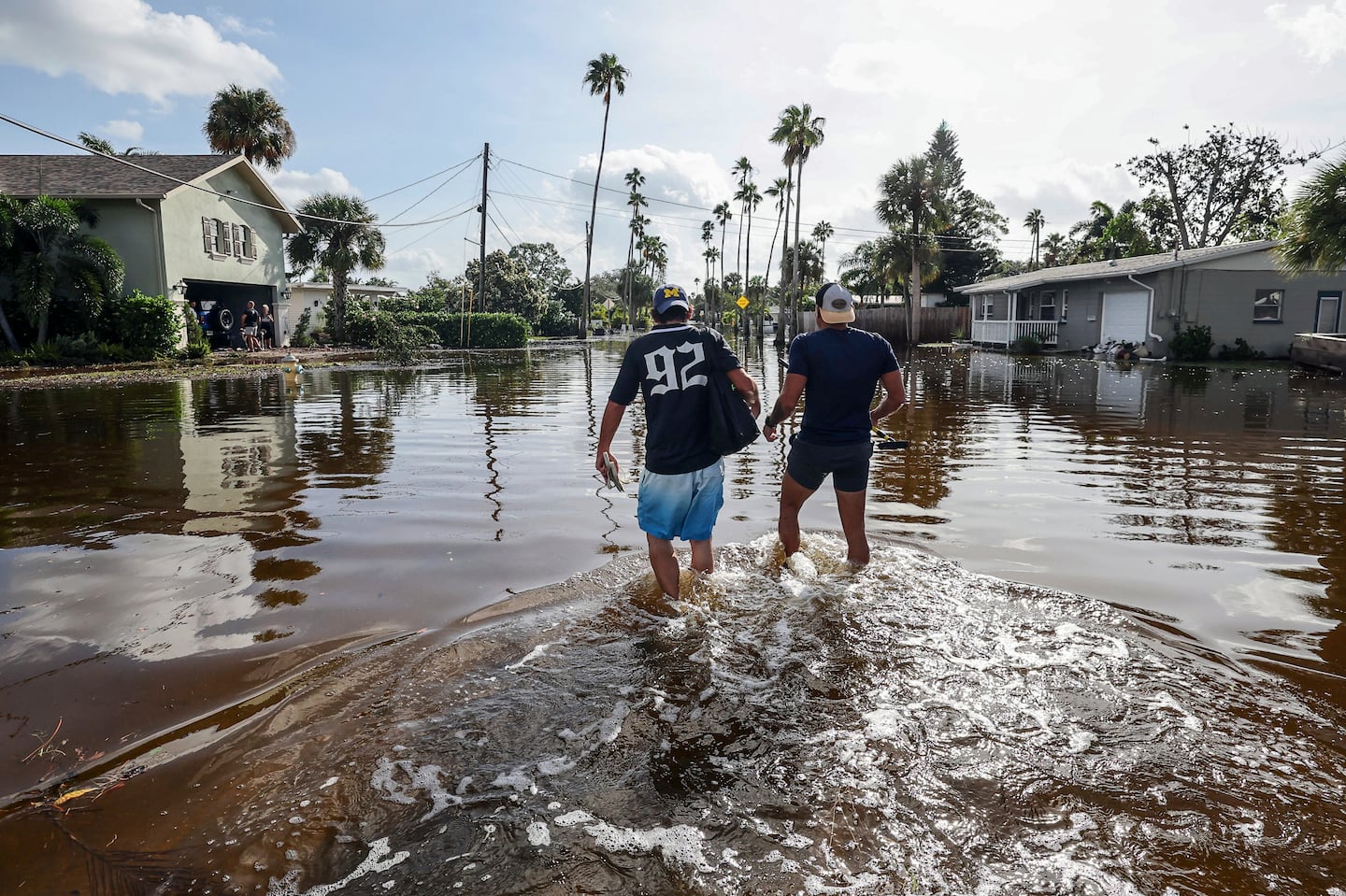 Thomas Chaves, left, and Vinny Almeida walk through floodwaters from Hurricane Helene to reach Chaves's mother's house in St. Petersburg, Fla., Friday.