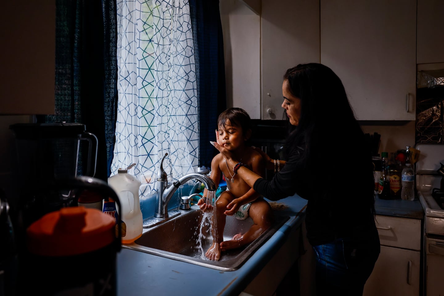 Gerrilee Thou rinses her 2-year-old son Ace at the kitchen sink in their Malden home. Thou, a mother of six, is struggling to make ends meet while her husband, Vibol, is detained by immigration authorities.