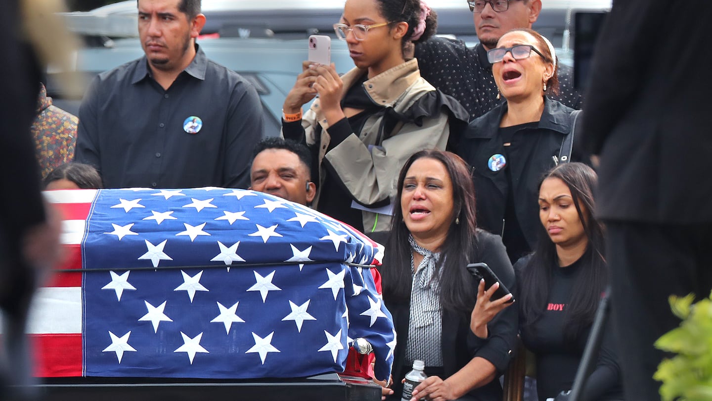 Sandra Garcia (center) sits with other family members as the flag-draped casket of her son, Enrique, is carried by Massachusetts State troopers. Enrique Delgado-Garcia’s funeral service was held Saturday outside at the Mercadante Funeral Home in Worcester.