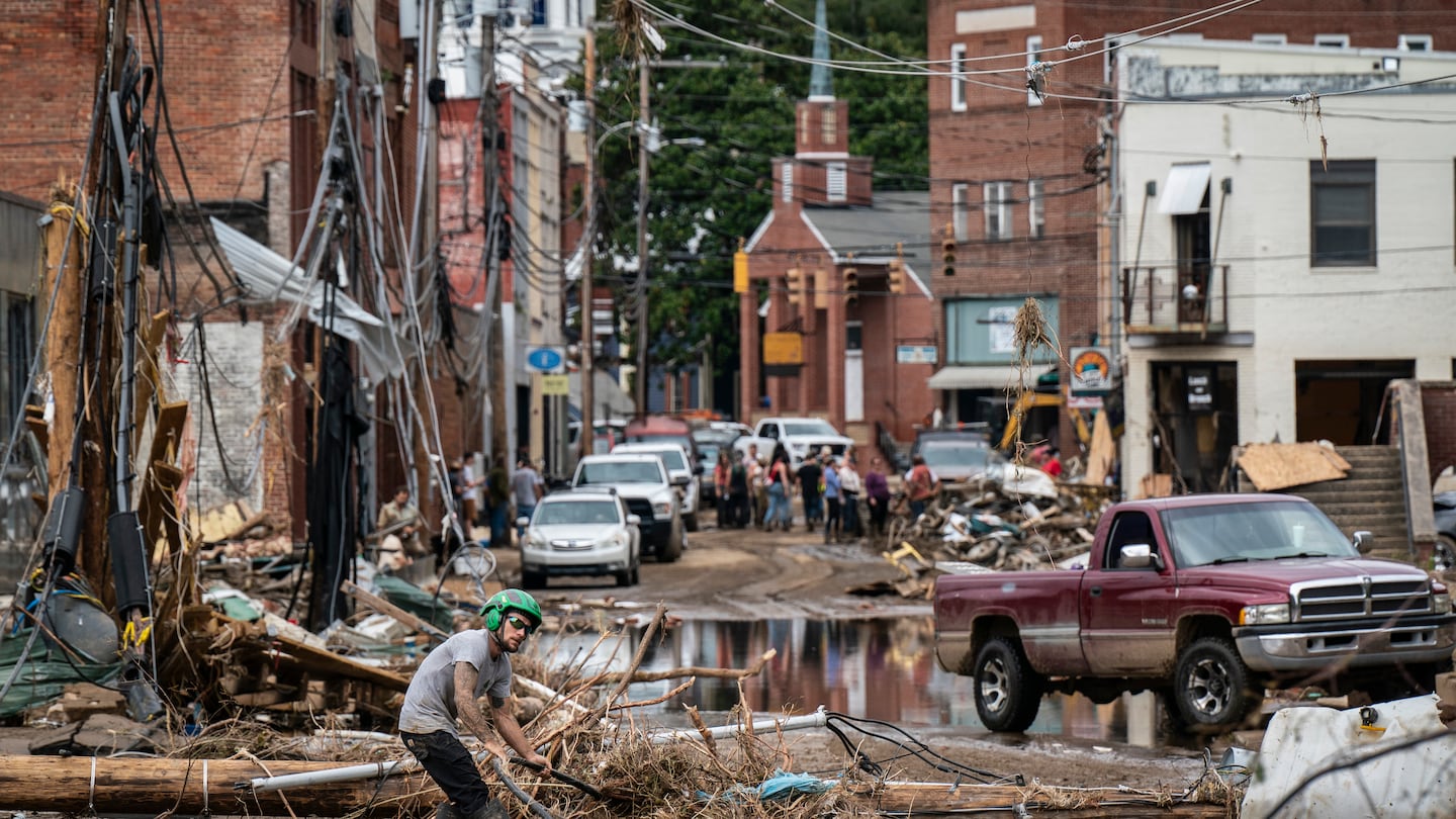 Workers, community member, and business owners clean up debris in the aftermath of Hurricane Helene in Marshall, N.C., on Monday.