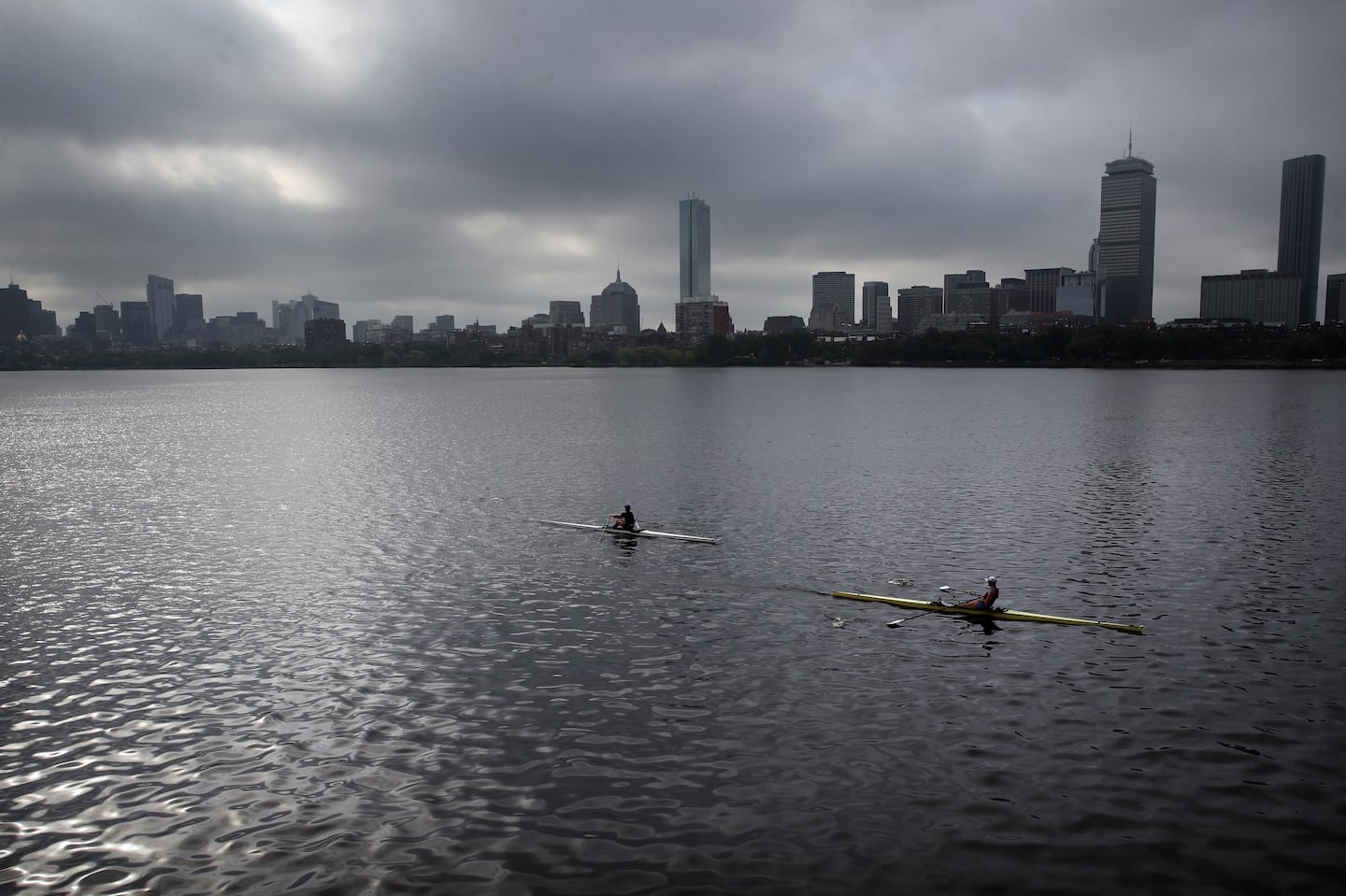 Rowers pass down the Charles River in Boston on a cloudy day.