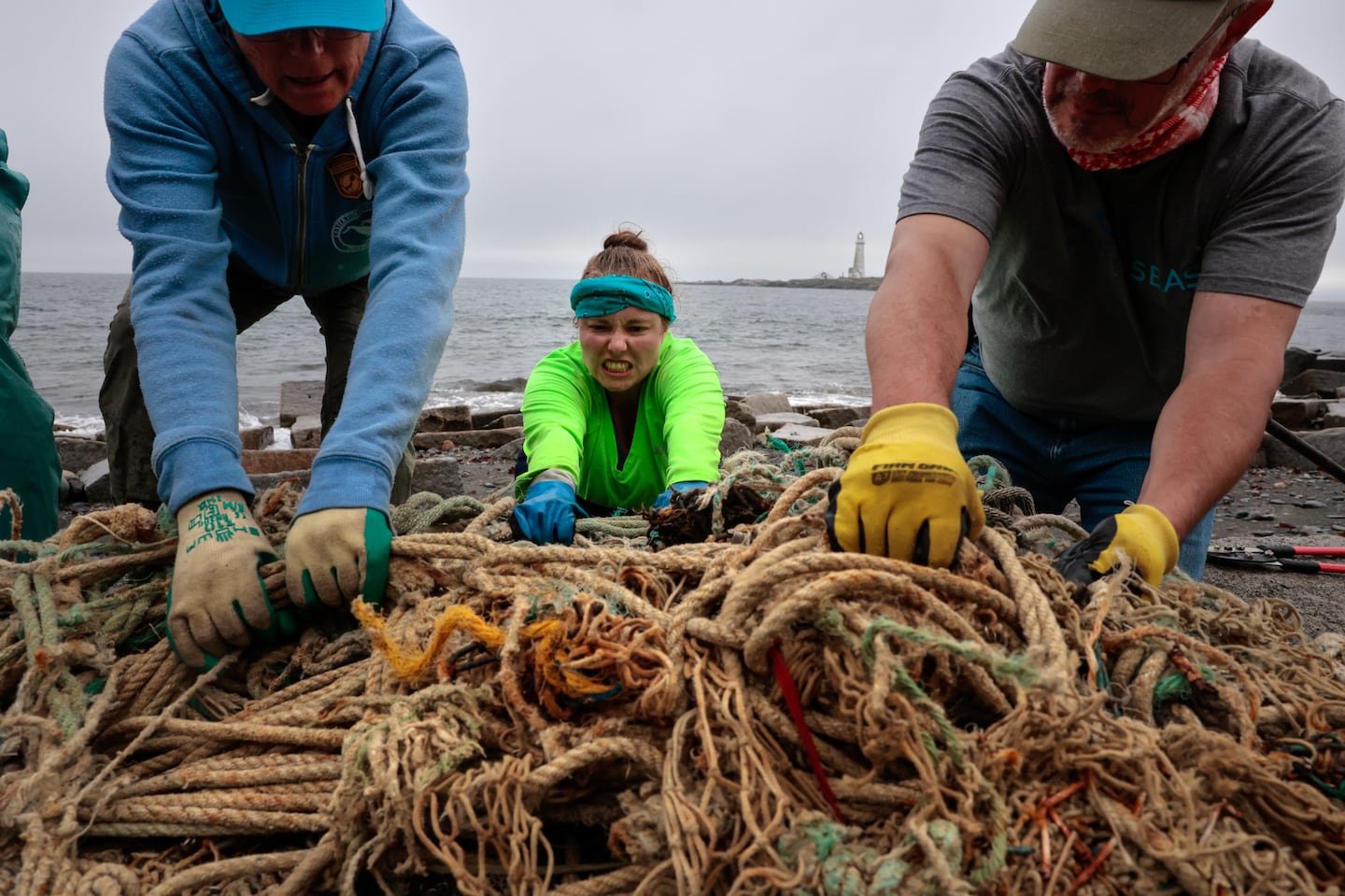 Laura Ludwig (left), director of the Marine Debris and Plastics Program at the Center for Coastal Studies, worked to dislodge a snarl of rope on Great Brewster Island in Boston Harbor with volunteers Adrianne Lovuolo and John Yonce.