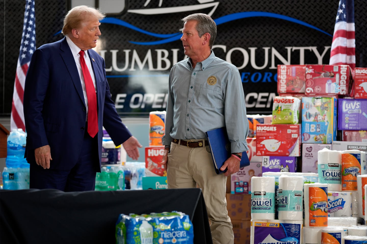 Republican presidential nominee former president Donald Trump talks with Georgia Governor Brian Kemp after speaking at a temporary relief shelter as he visits areas impacted by Hurricane Helene, Friday, Oct. 4, 2024, in Evans, Ga.