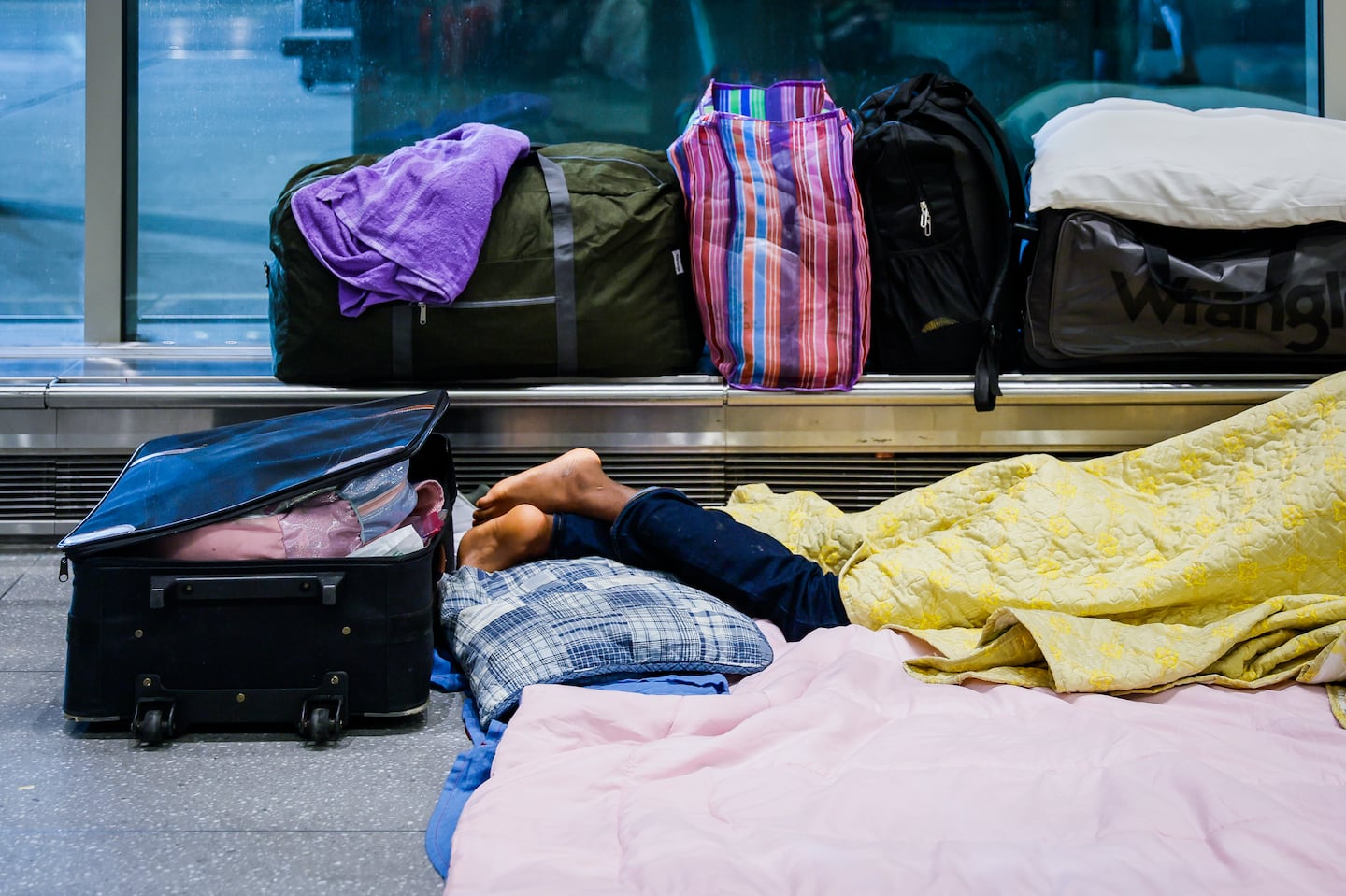 A migrant sleeping at Logan Airport in July. The Healey administration has since banned migrants from staying there, as the state struggles with an influx of new arrivals.