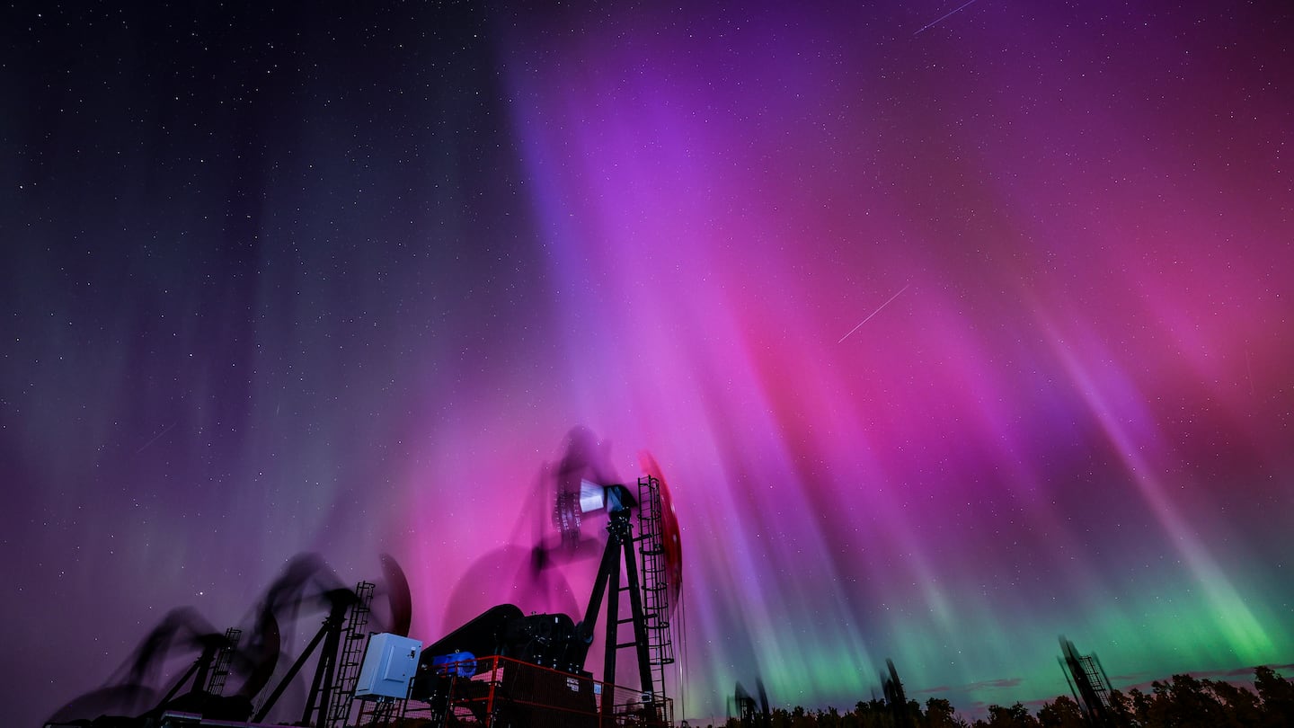 An aurora borealis, also known as the northern lights, makes an appearance over pumpjacks as they draw out oil and gas from well heads near Cremona, Alta., on Oct. 10.