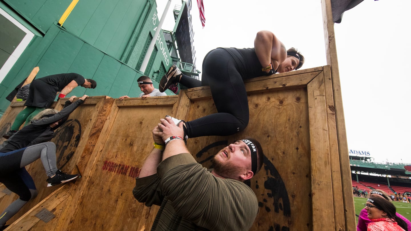 Participants help one another during a Spartan Race at Fenway Park in 2018.