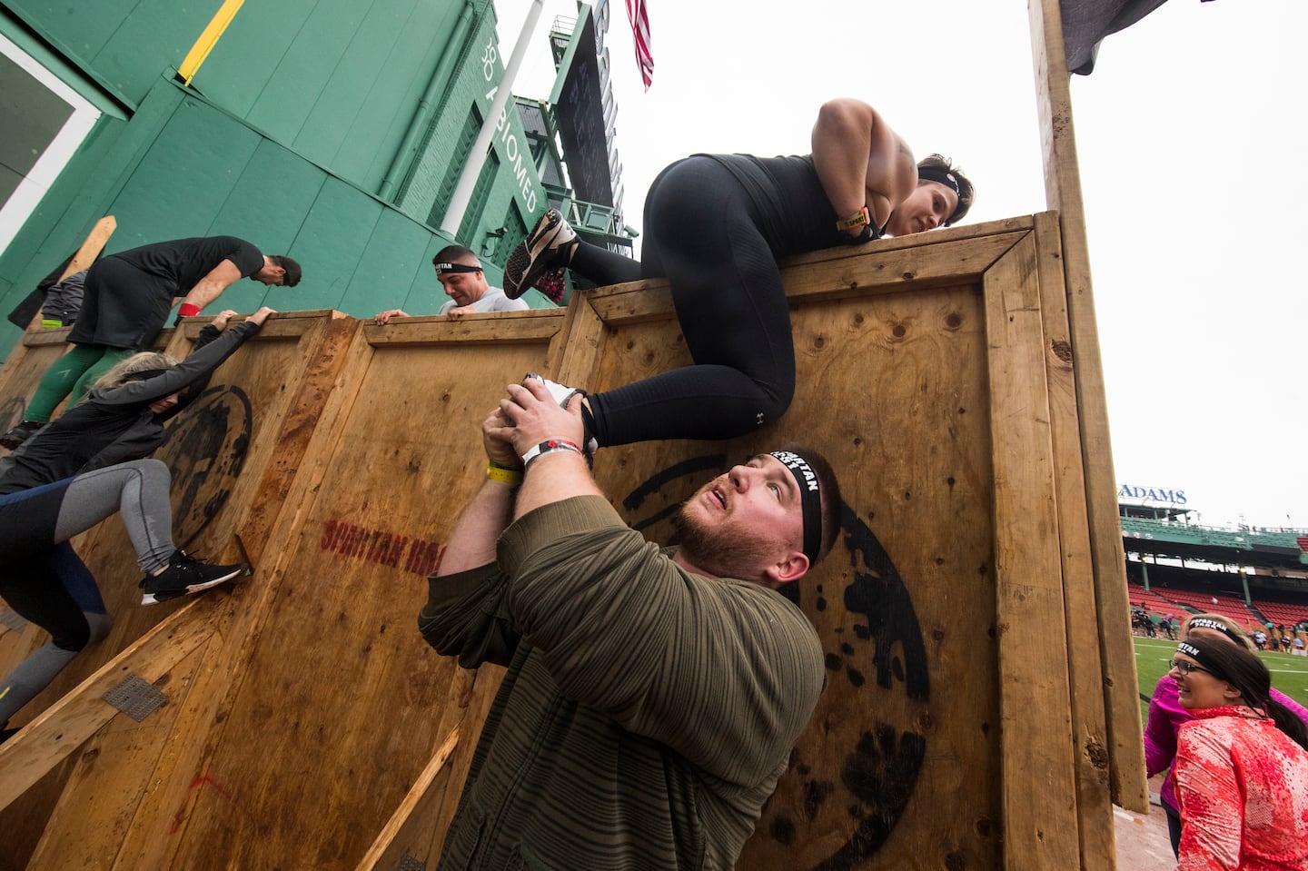 Participants help one another during a Spartan Race at Fenway Park in 2018.