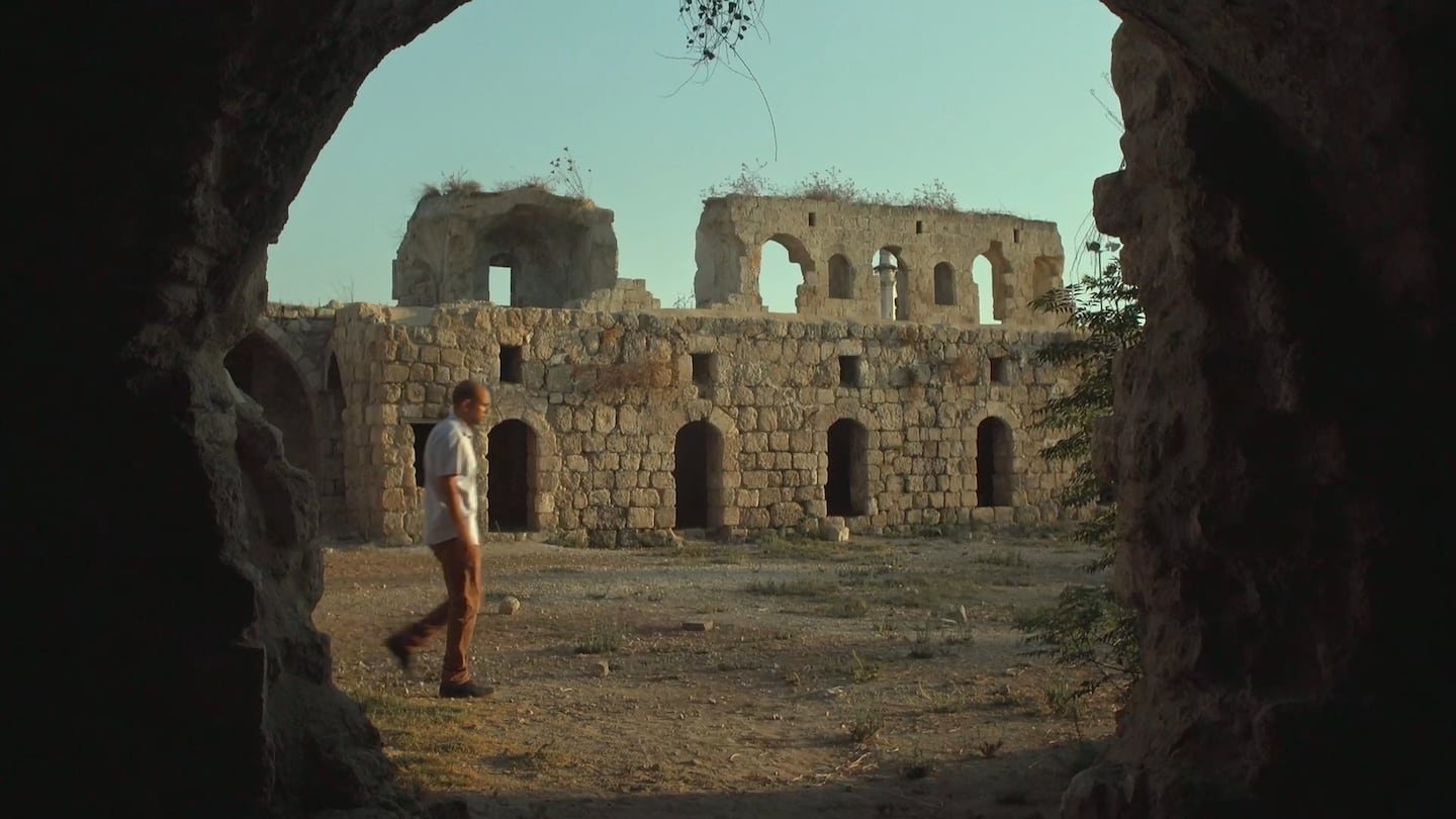 In this still from "Lyd," Orwa Switat, an urban planner, walks through the ruins of Khan el-Hilu, a 19th-century inn.