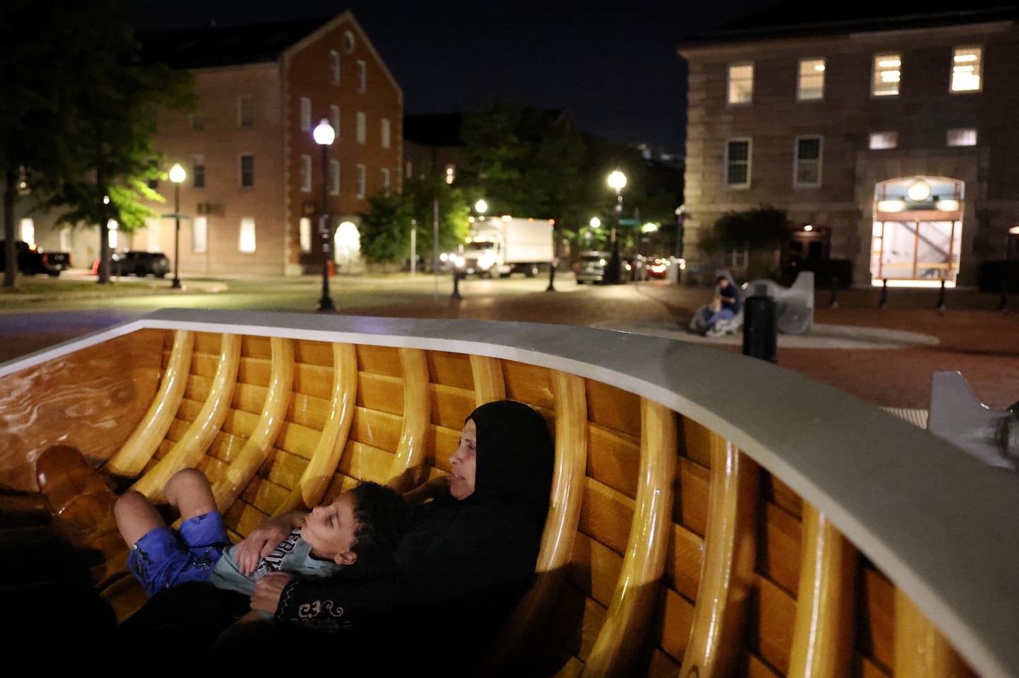 Amira Abumuhaisen held onto her grandson Aser as the two sat in a sculpture along the waterfront in Boston.