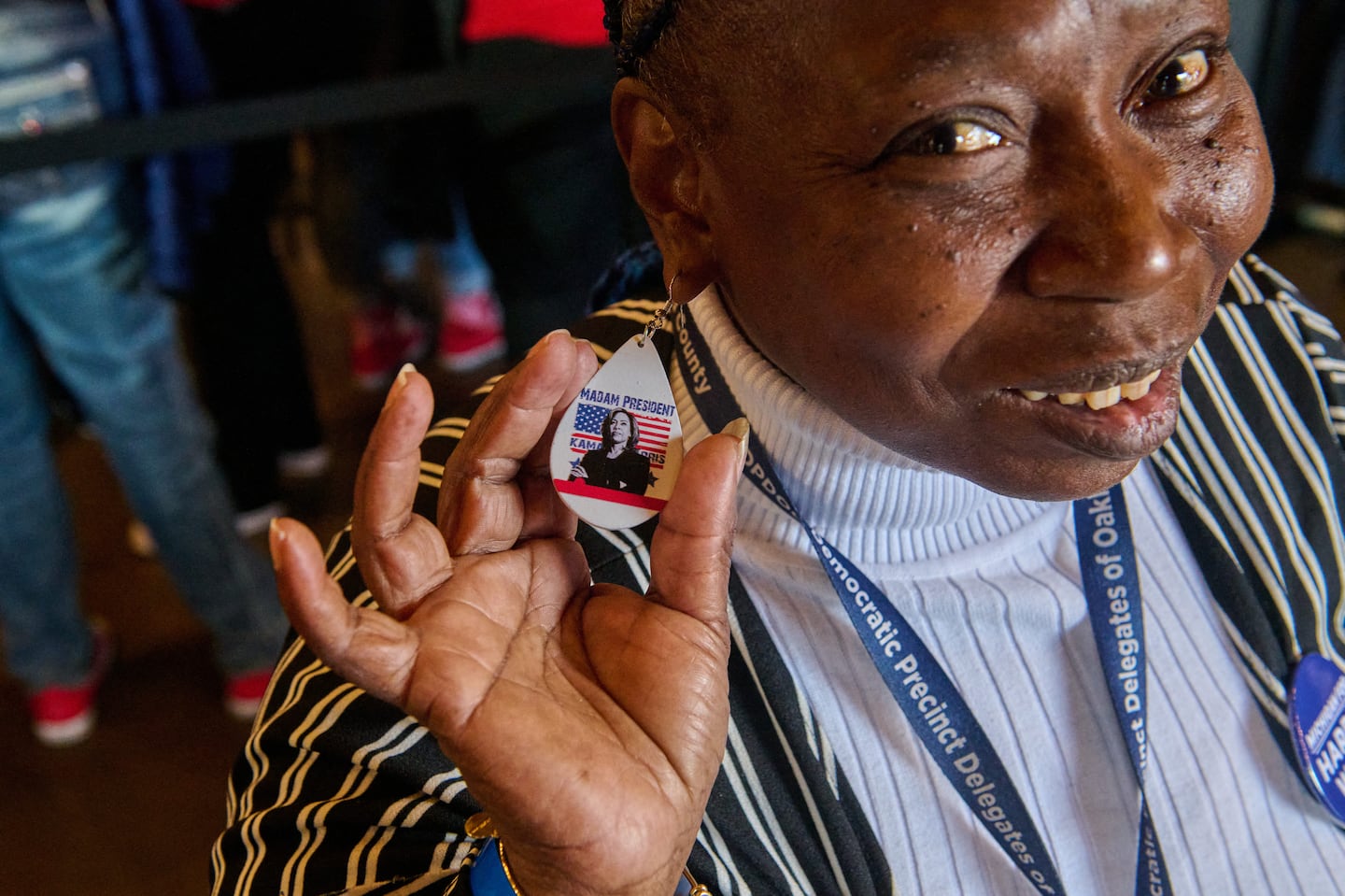 Veronica Taylor, 65, of Pontiac, Mich., shows her unique earrings featuring Vice President Kamala Harris during a campaign event in Clawson on Oct. 14,,