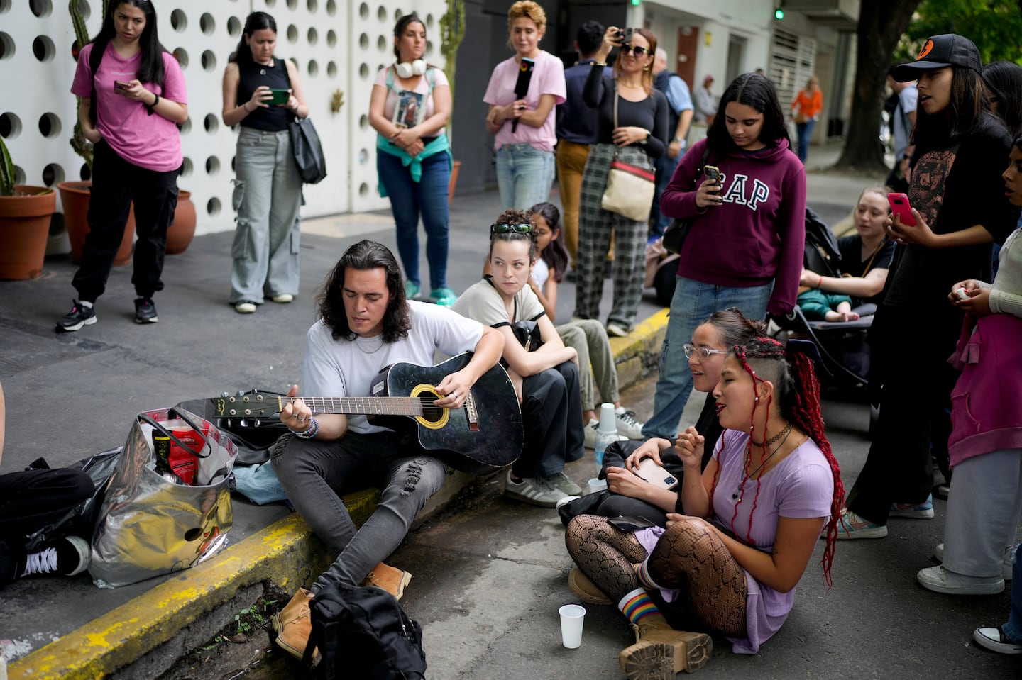 Fans sing in honor of former One Direction singer Liam Payne outside the hotel where he was found dead after falling from a balcony in Buenos Aires, Argentina, Thursday, Oct. 17, 2024.