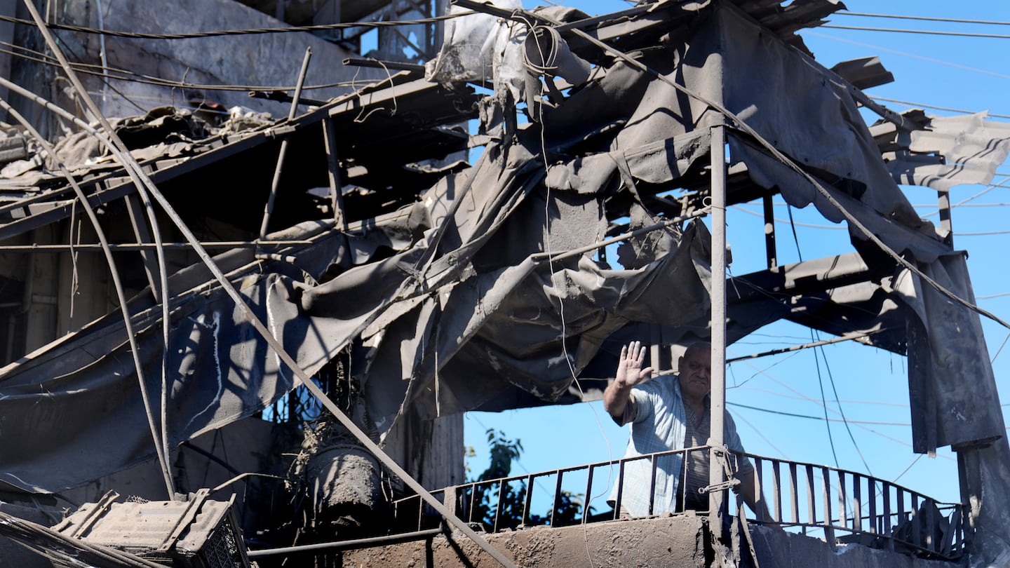 A man waves from his shattered house at the site of Israeli airstrikes that destroyed buildings facing the city's main government hospital in a densely-populated neighborhood, in southern Beirut, Lebanon, on Oct. 22.