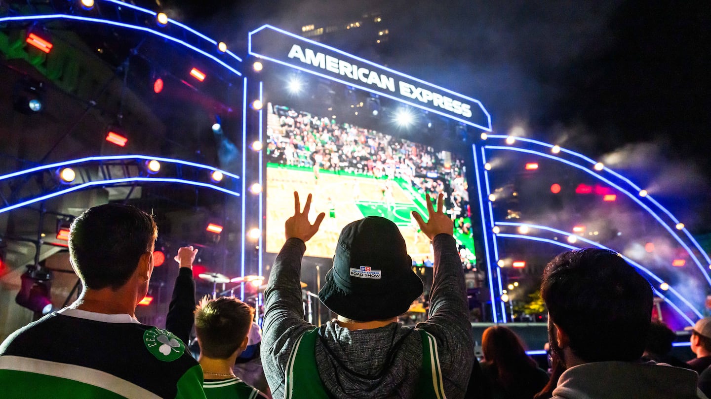 A spectator puts up three fingers on each hand to anticipate a 3-point shot attempt while watching a livestream of the season opener Boston Celtics game at City Hall Plaza in downtown Boston on Tuesday night.