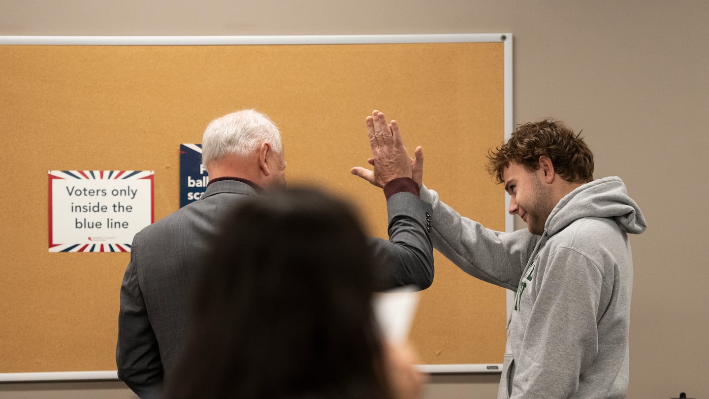 Democratic vice presidential nominee Minnesota Gov. Tim Walz (left) high-fives his son, Gus Walz, a first-time voter, as they casted their ballots during early voting at the Ramsey County Elections office in St. Paul, Minn., Wednesday.