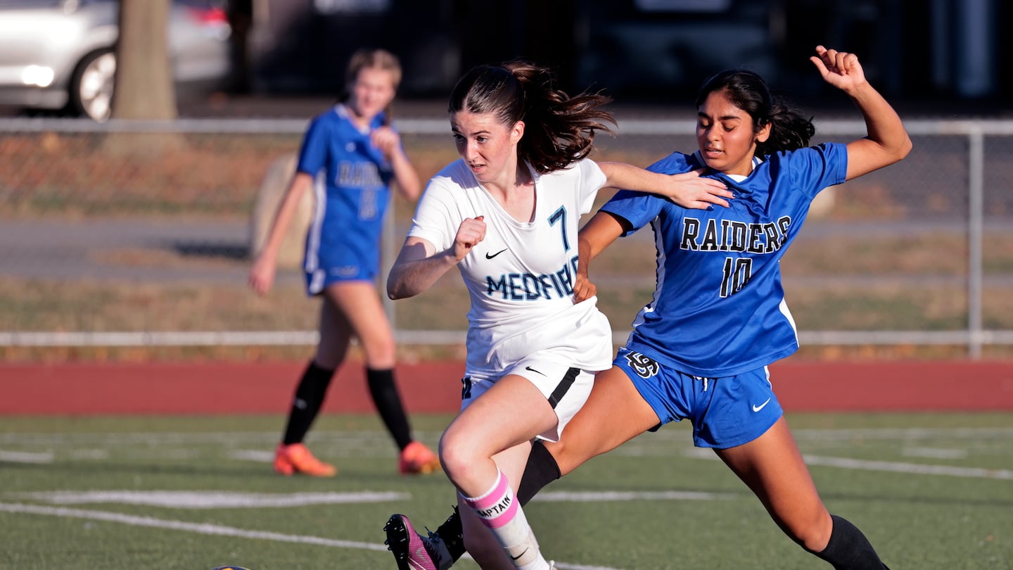 Medfield’s Juliet Lane (No. 7) advances the ball past Dover-Sherborn's Raina Patel (No. 10).