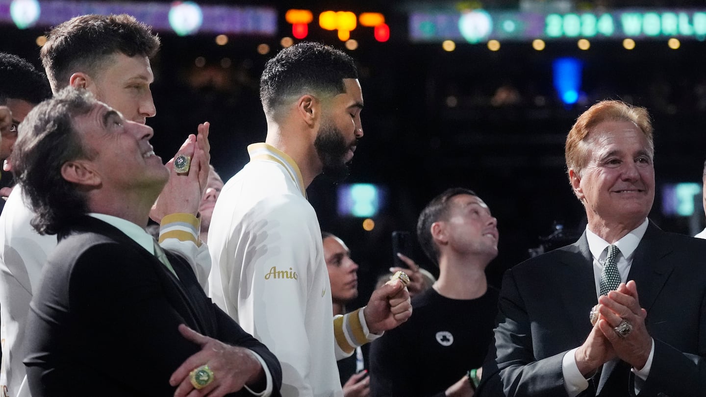 Celtics owners Wyc Grousbeck (left) and Steve Pagliuca (right) looked on as the championship banner was raised at TD Garden Tuesday night. Celtics forward Jayson Tatum (center) checked out his new ring.