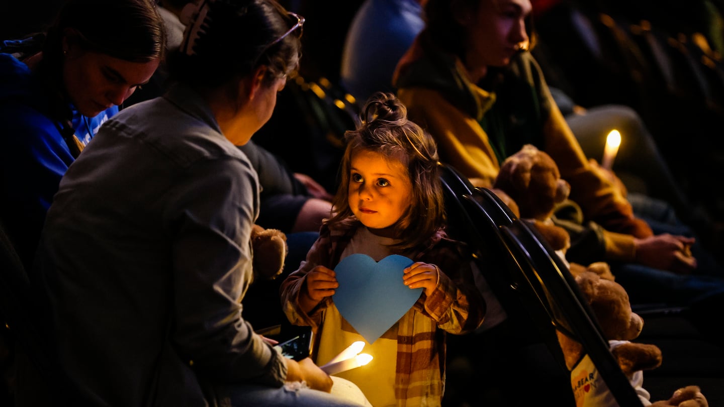 A young girl with a blue heart, symbolizing Lewiston's strength, during Friday's memorial service at The Colisée marking one year since the mass shooting that killed 18 people.