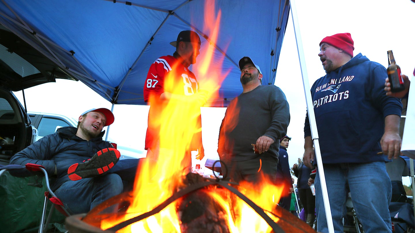 Fans tailgate with a fire pit roaring in the Gillette Stadium parking lot on Oct. 10, 2019.