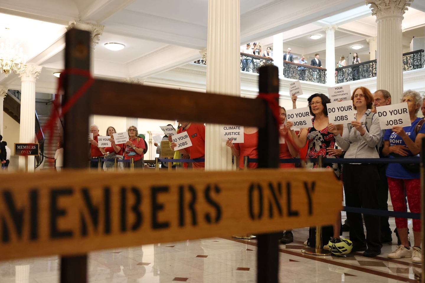 Members of 350 Mass, which advocates for ending the use of fossil fuels, protested outside of the House Chamber at the State House in July.