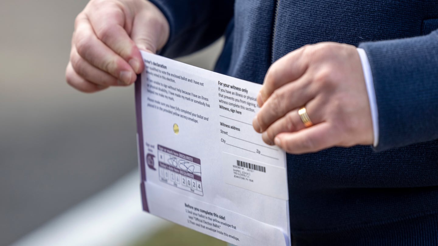 Pennsylvania Governor Josh Shapiro carries his mail-in ballot to a dropbox on Saturday, Oct. 26, 2024, in Abington, Pa.