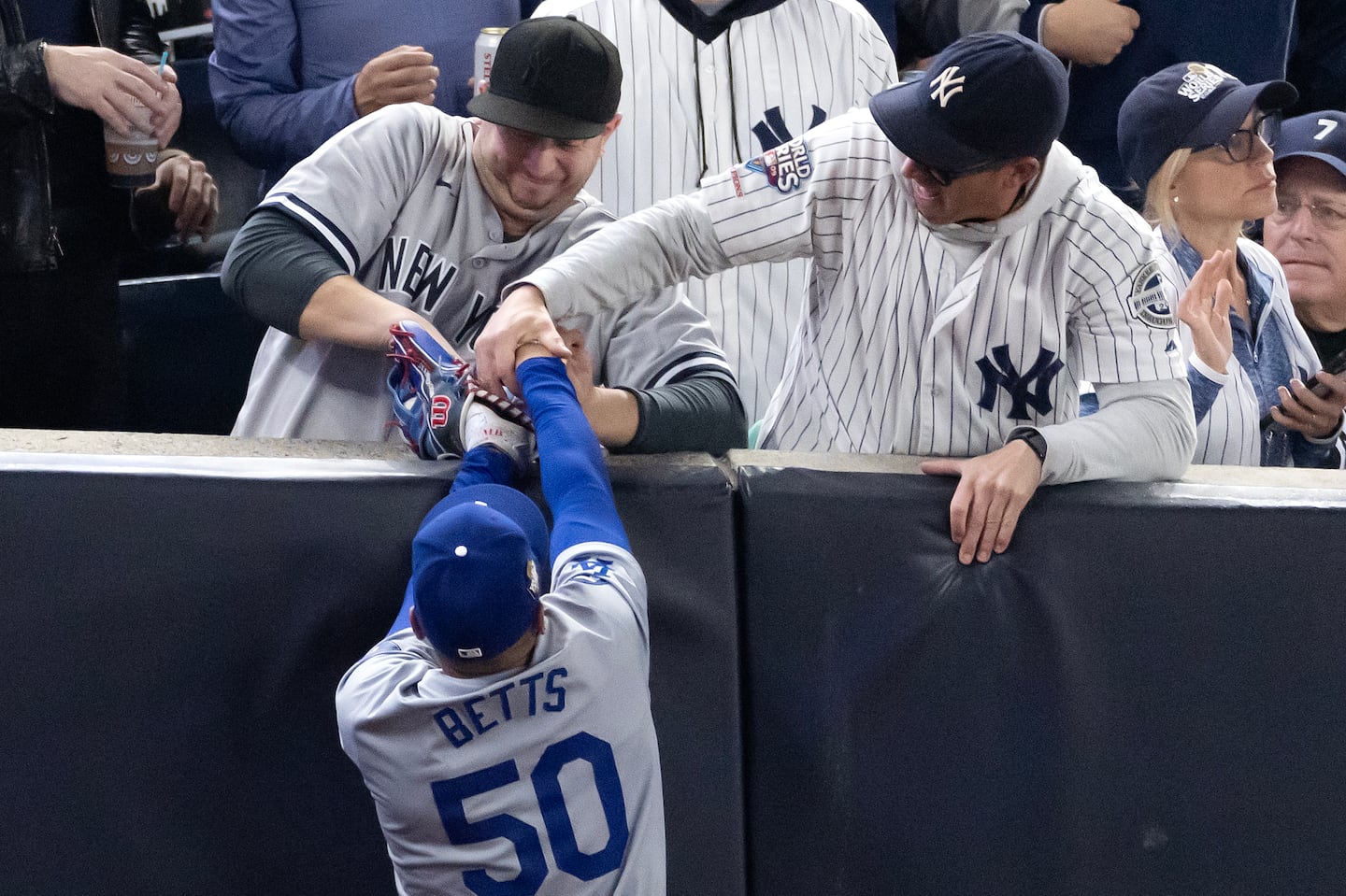 Fans interfere with Mookie Betts as he attempts to catch a fly ball in foul territory during the first inning of Game Four of the 2024 World Series.