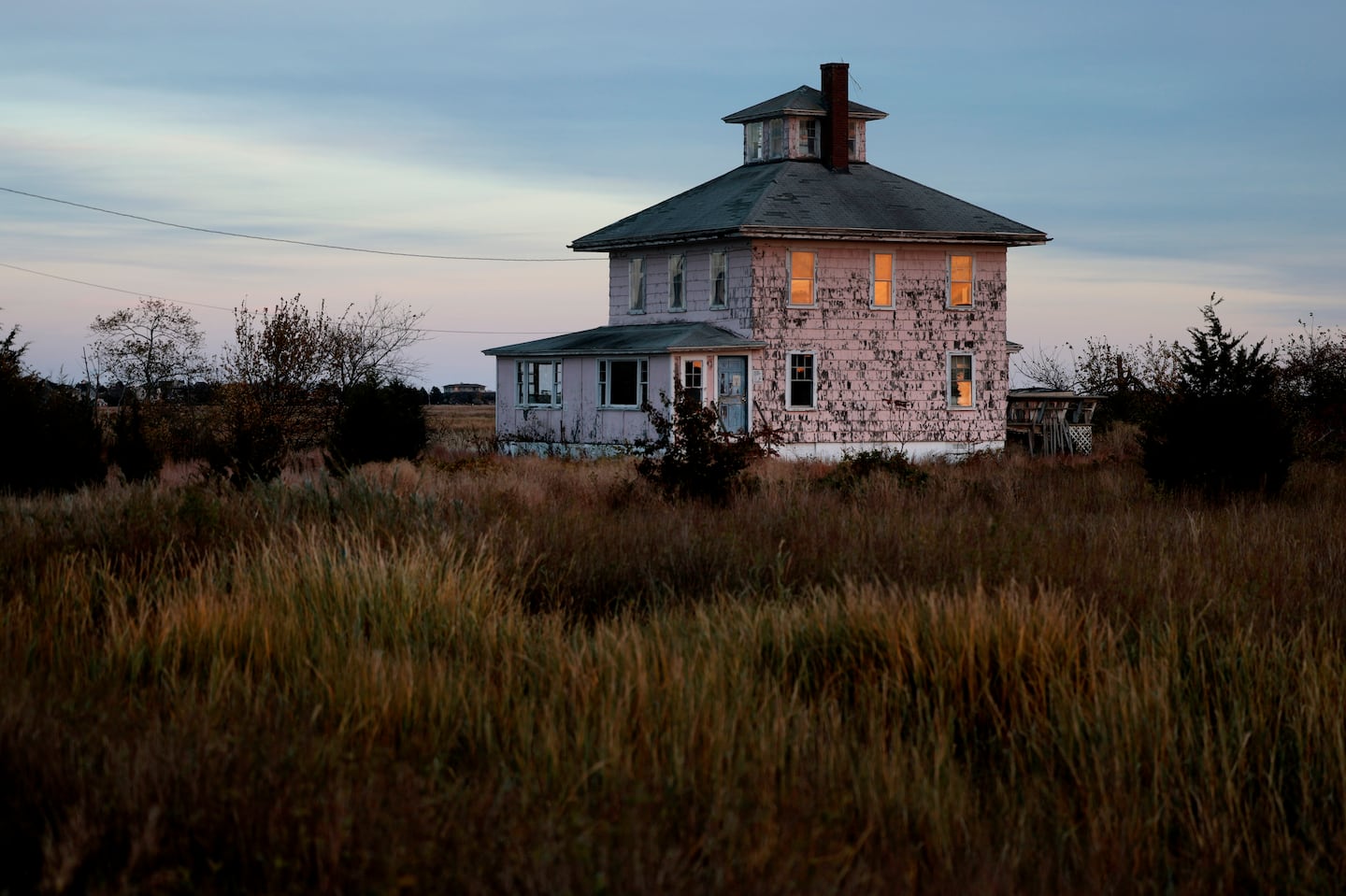 The setting sun is reflected in the windows of the iconic Pink House on the causeway to Plum Island. The building is owned by US Fish and Wildlife, and they've announced they are tearing it down.