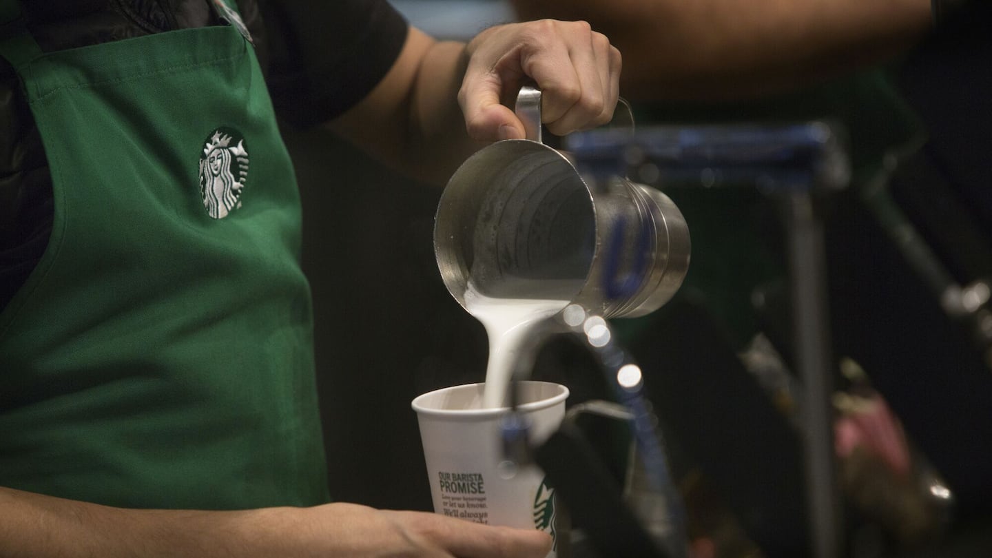 A barista pours frothed milk into a drink inside a Starbucks Corp. coffee shop in New York.