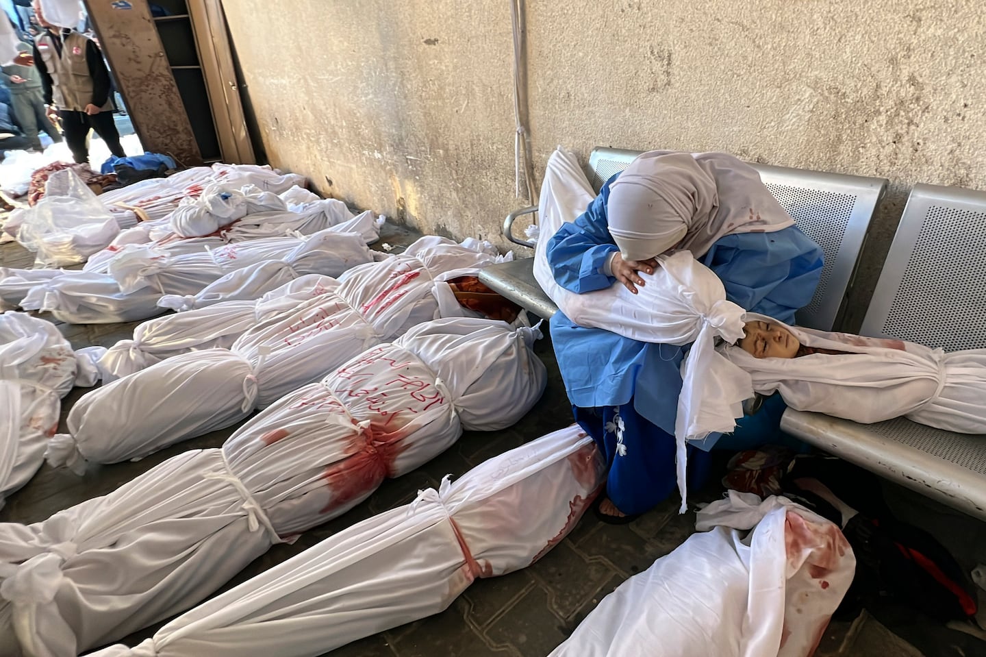 A Palestinian woman reacts over the body of a child as she sits by bodies of Palestinians killed by Israeli airstrikes on Jabaliya refugee camp, at the Indonesian hospital, northern Gaza Strip, Nov. 18, 2023.